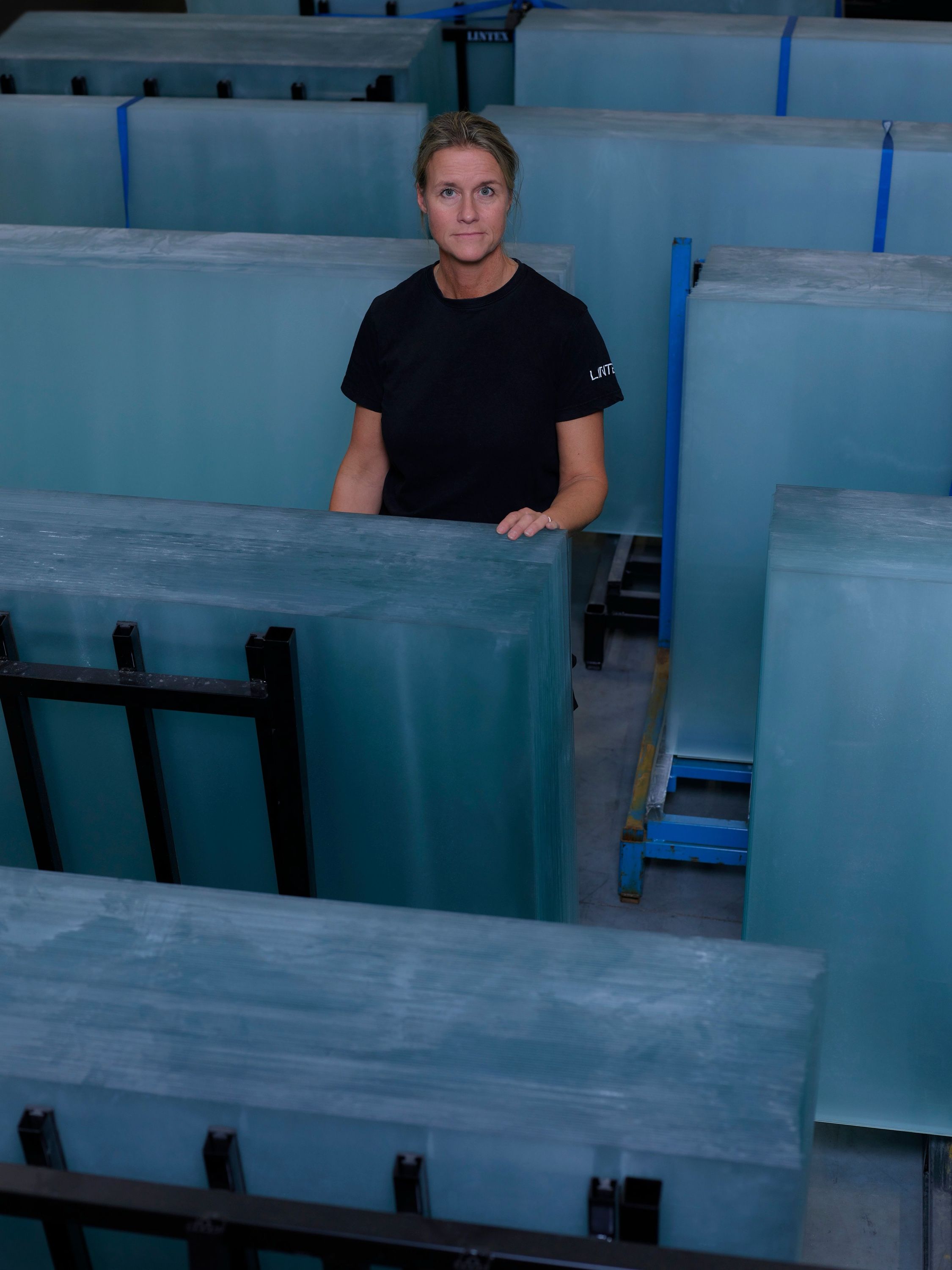 A worker in the factory among stacked glass sheets