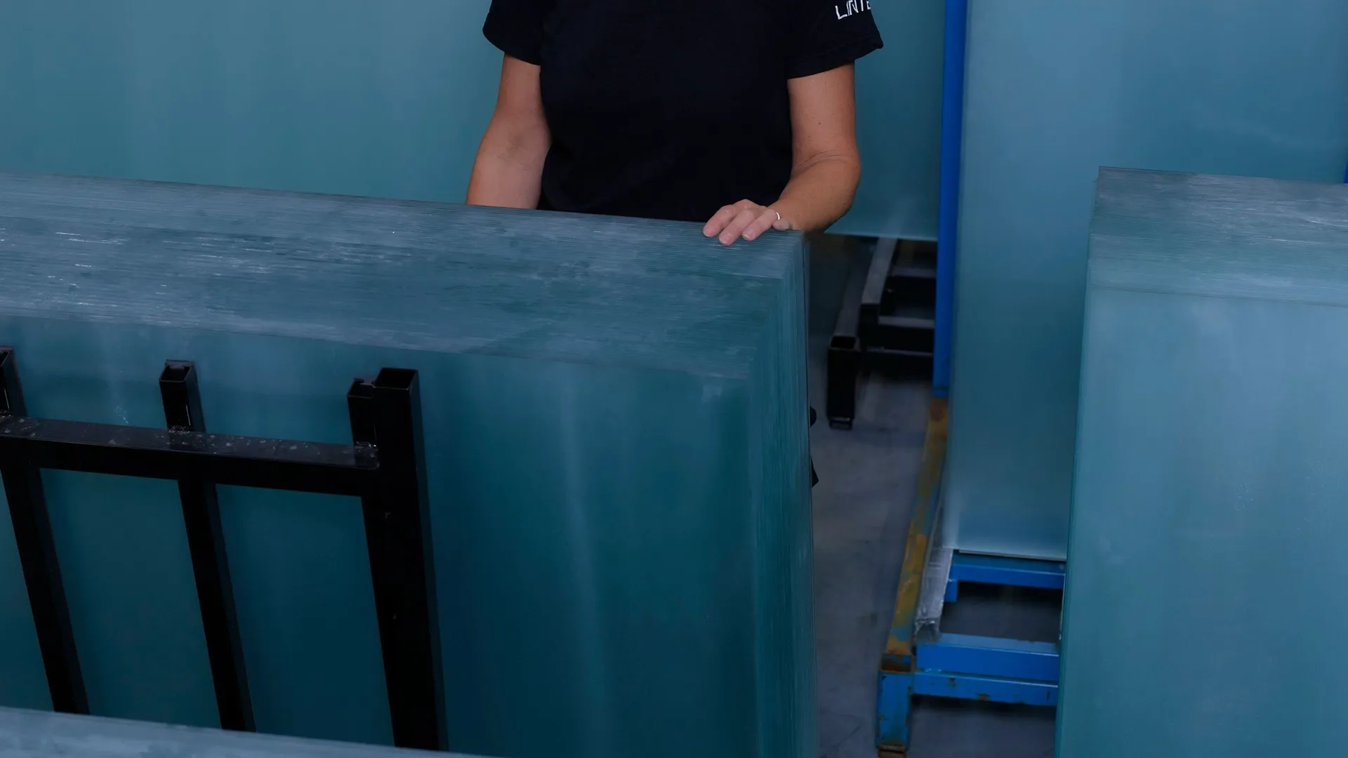 Un ouvrier de l’usine debout au milieu de plaques de verre empilées