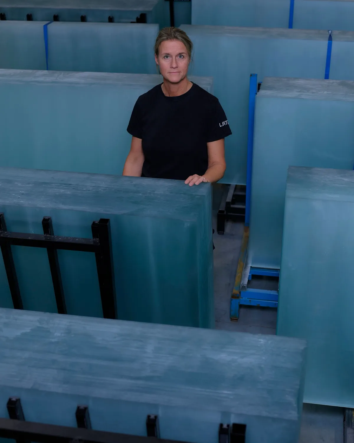 A worker in the factory among stacked glass sheets