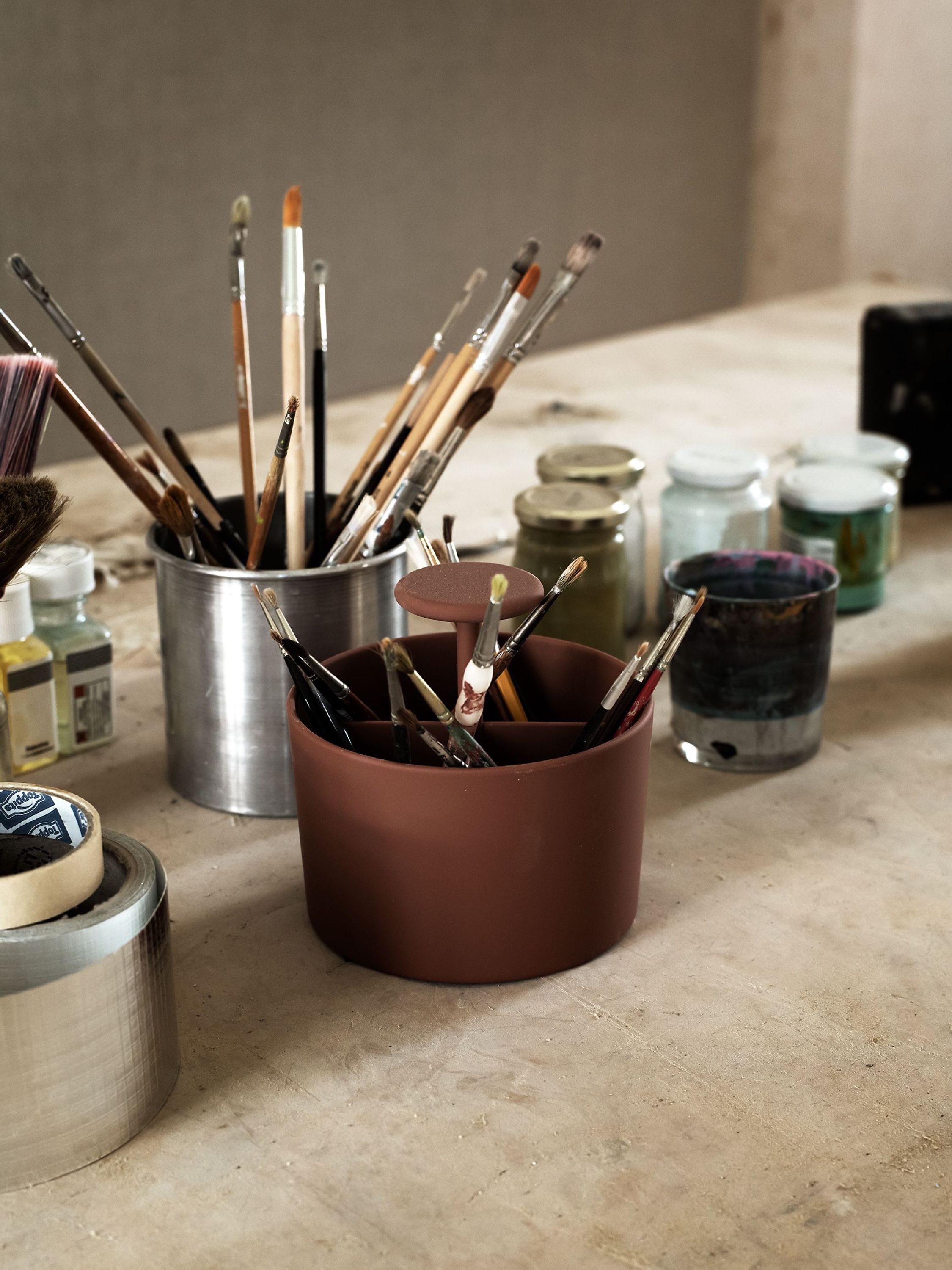 Paintbrushes in jars and pots on a work table
