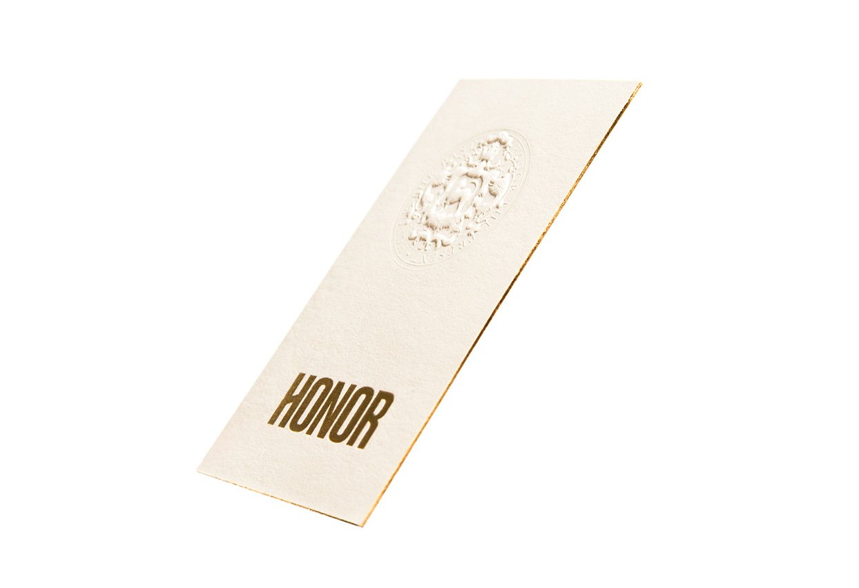 Honor clothing hang tag, gold logo on cream paper with embossed seal, print design by RoAndCo Studio