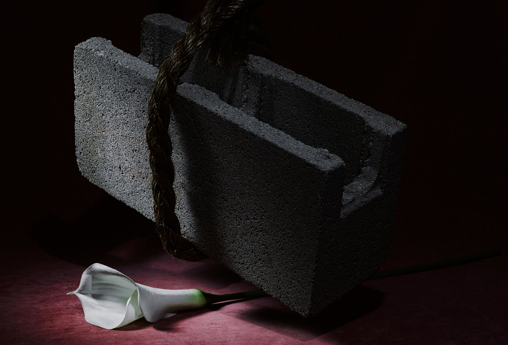 Still image of cinder block hanging over white calla lily flower for Romance Journal Issue 02 Resistance. Publication design, art direction, print design by RoAndCo.
