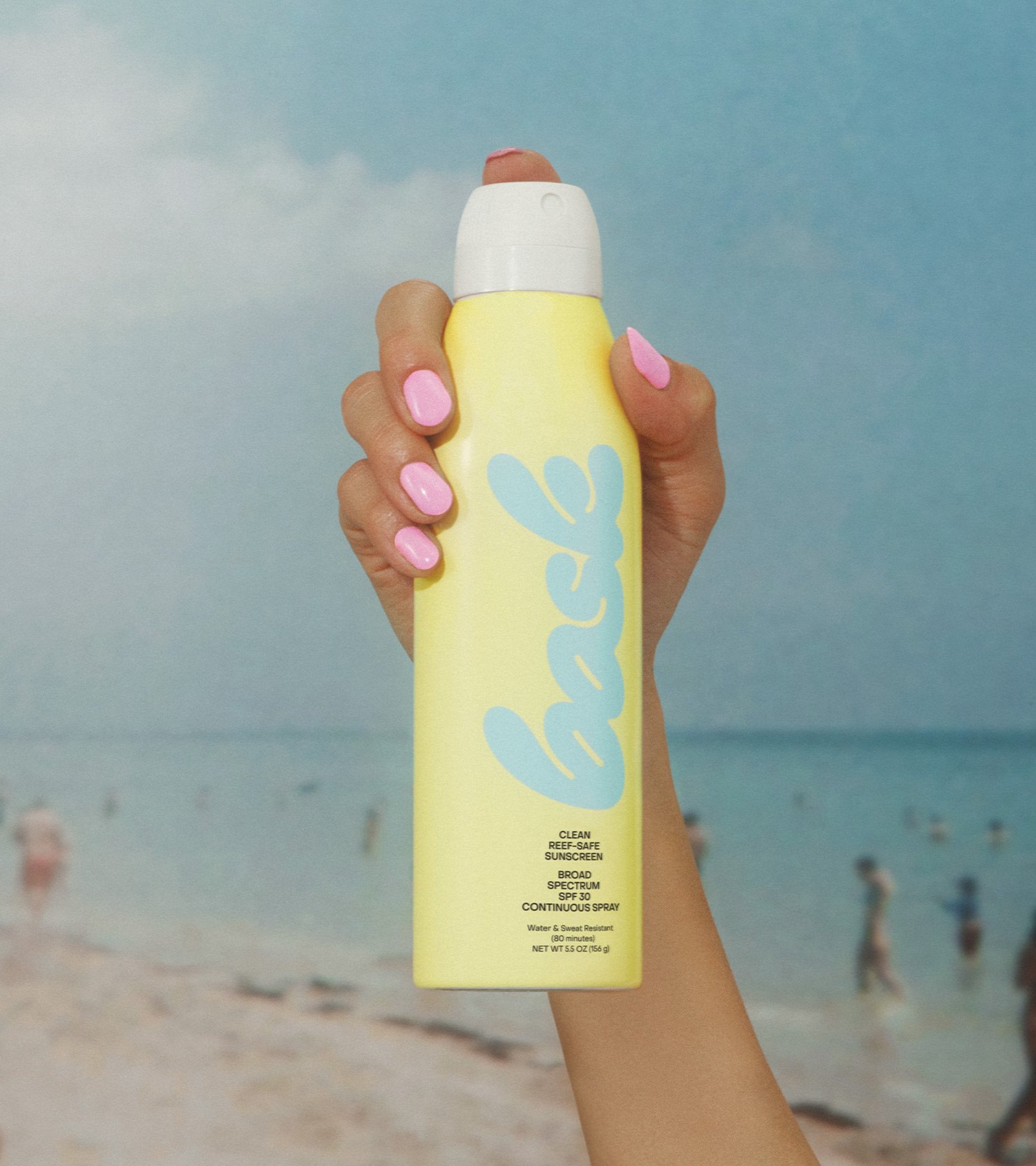 Bask Continuous Spray SPF 30 Held Up by Hand with Pink Manicure by the Beach, Art Direction by RoAndCo