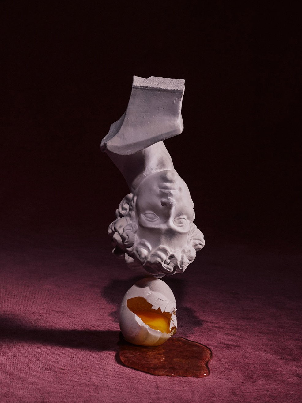 Still life image of upside down bust balancing on top of a broken egg. Romance Journal Issue 02 Resistance. Publication design, art direction, print design by RoAndCo.