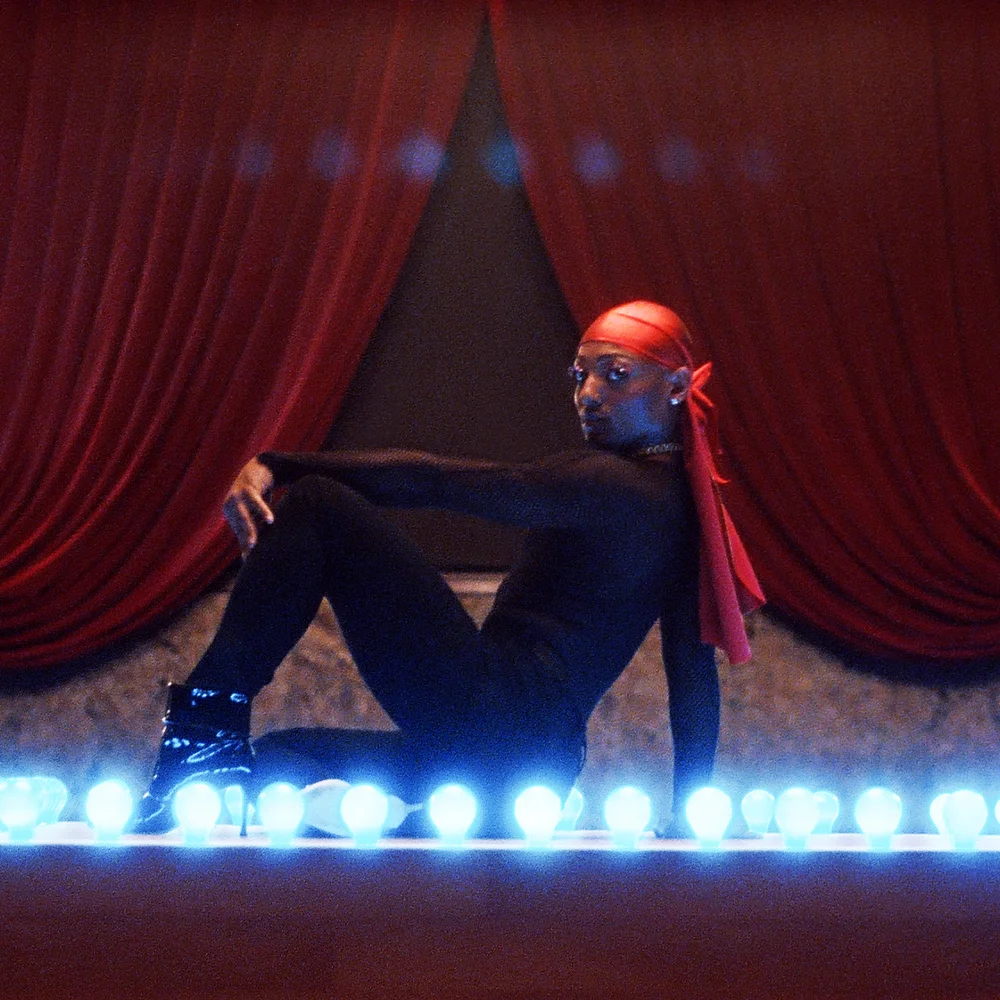 Alex Mugler posing on stage for Mac Viva Glam 25th Anniversary Campaign, by RoAndCo Studio