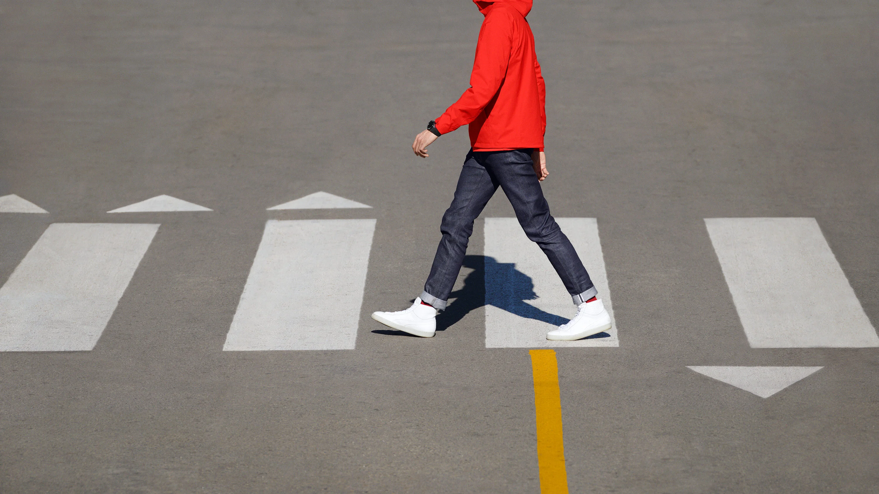Man crossing the street, wearing black Google Wear OS watch. Art Direction by RoAndCo Studio