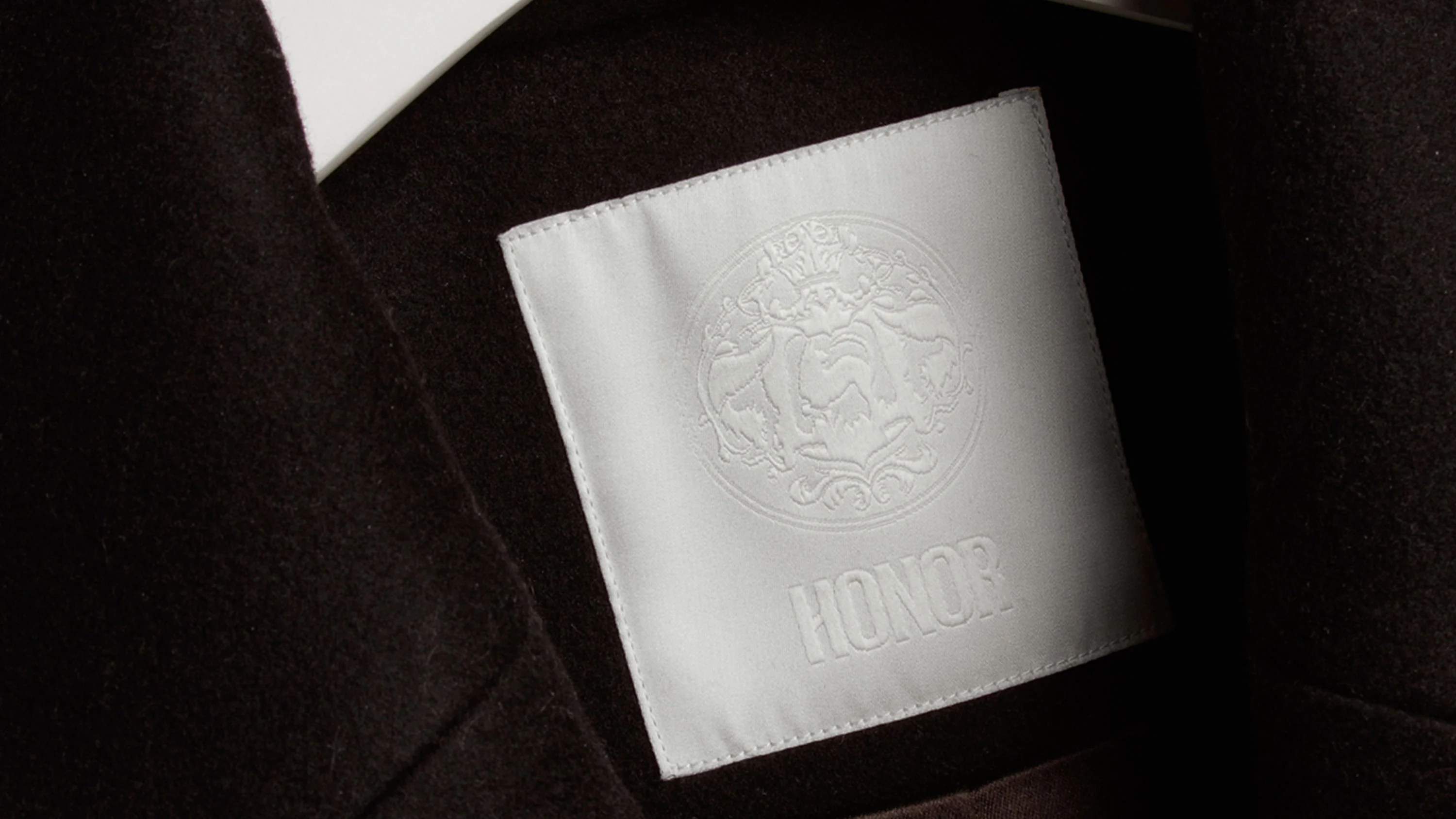Close up of sew-in Honor clothing tag, with brand seal, designed by RoAndCo