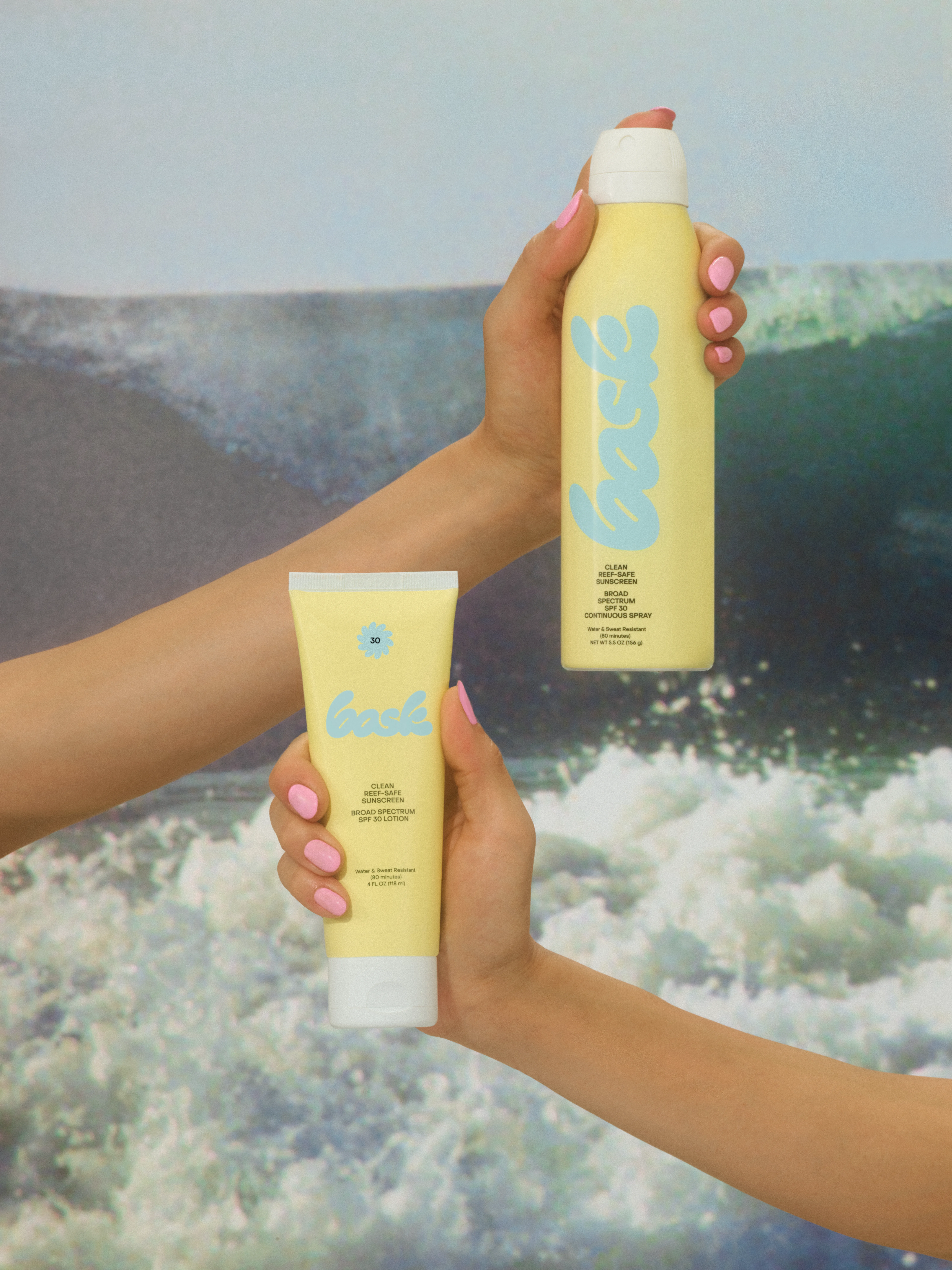Bask Yellow Lotion Tube and Yellow Continuous Spray Bottle held up against an Ocean Wave - Art Direction by RoAndCo