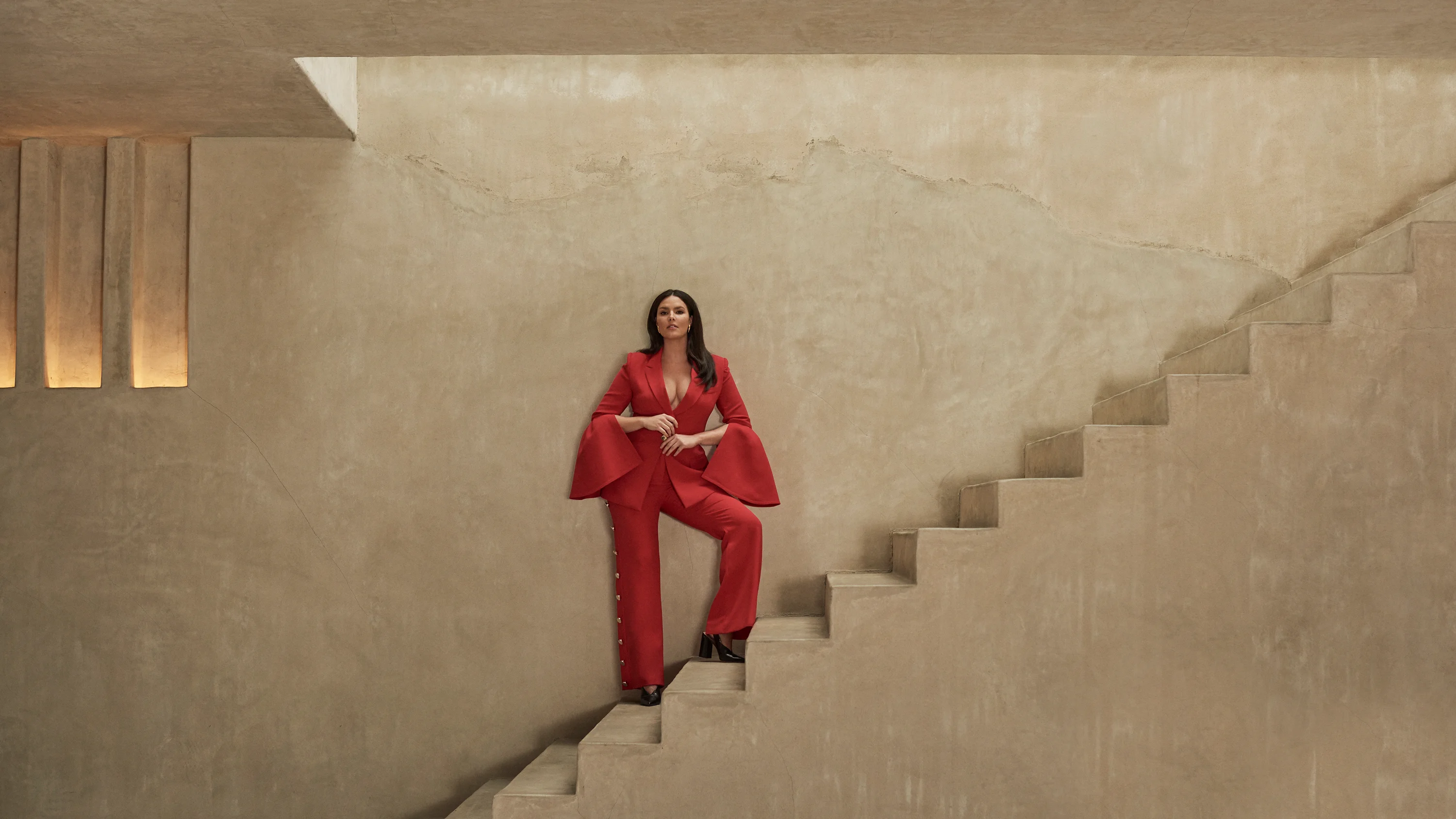 Model Candice Huffline wearing red power suit with dramatic sleeves, Ad campaign. Art Direction by RoAndCo