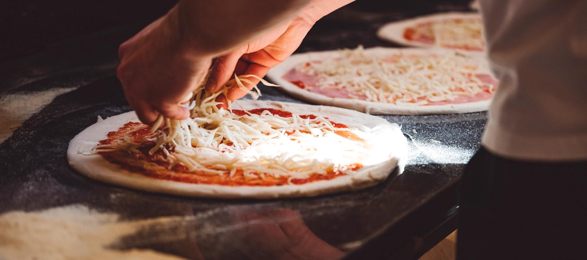 sprinkling cheese on a pizza