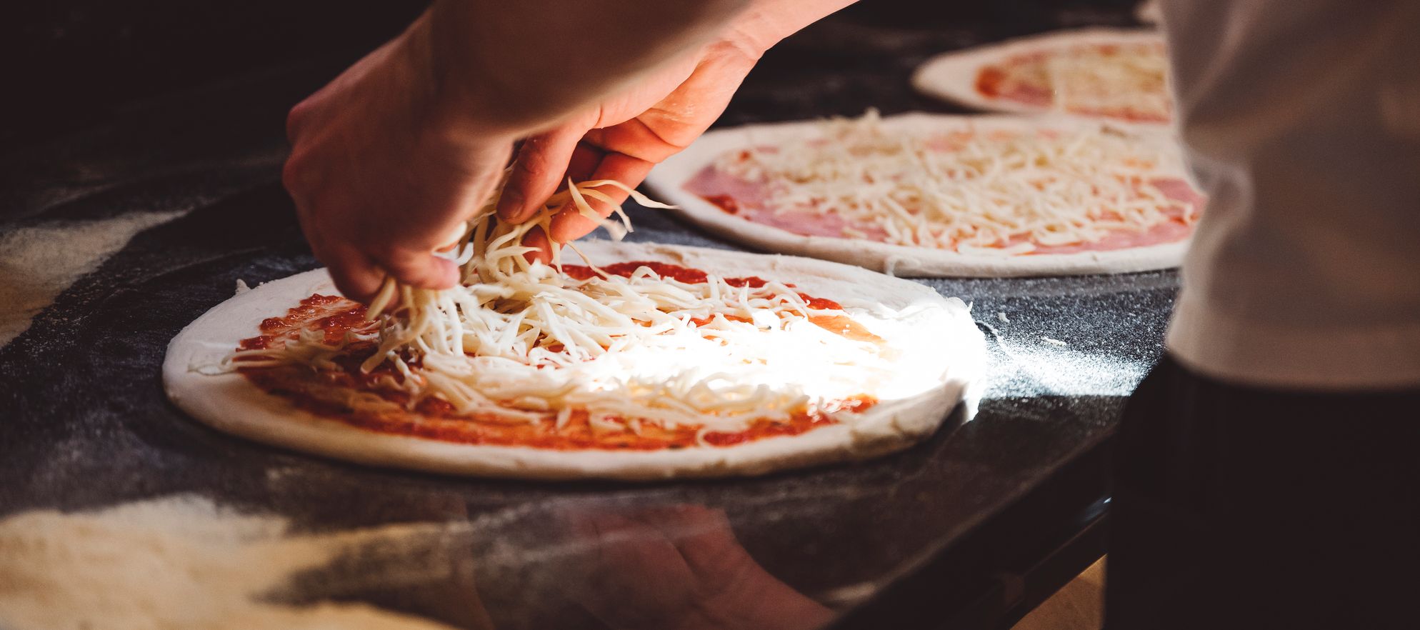 sprinkling cheese on a pizza