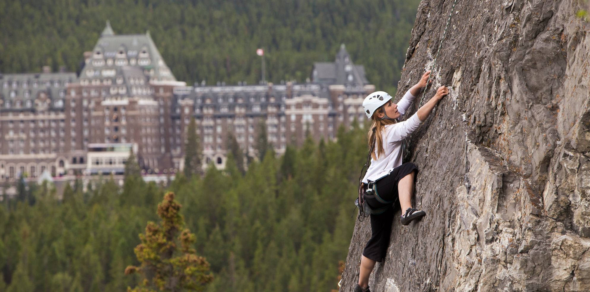 A climber ascends a cliff by the Chateau Lake Louise, Banff National Park, AB