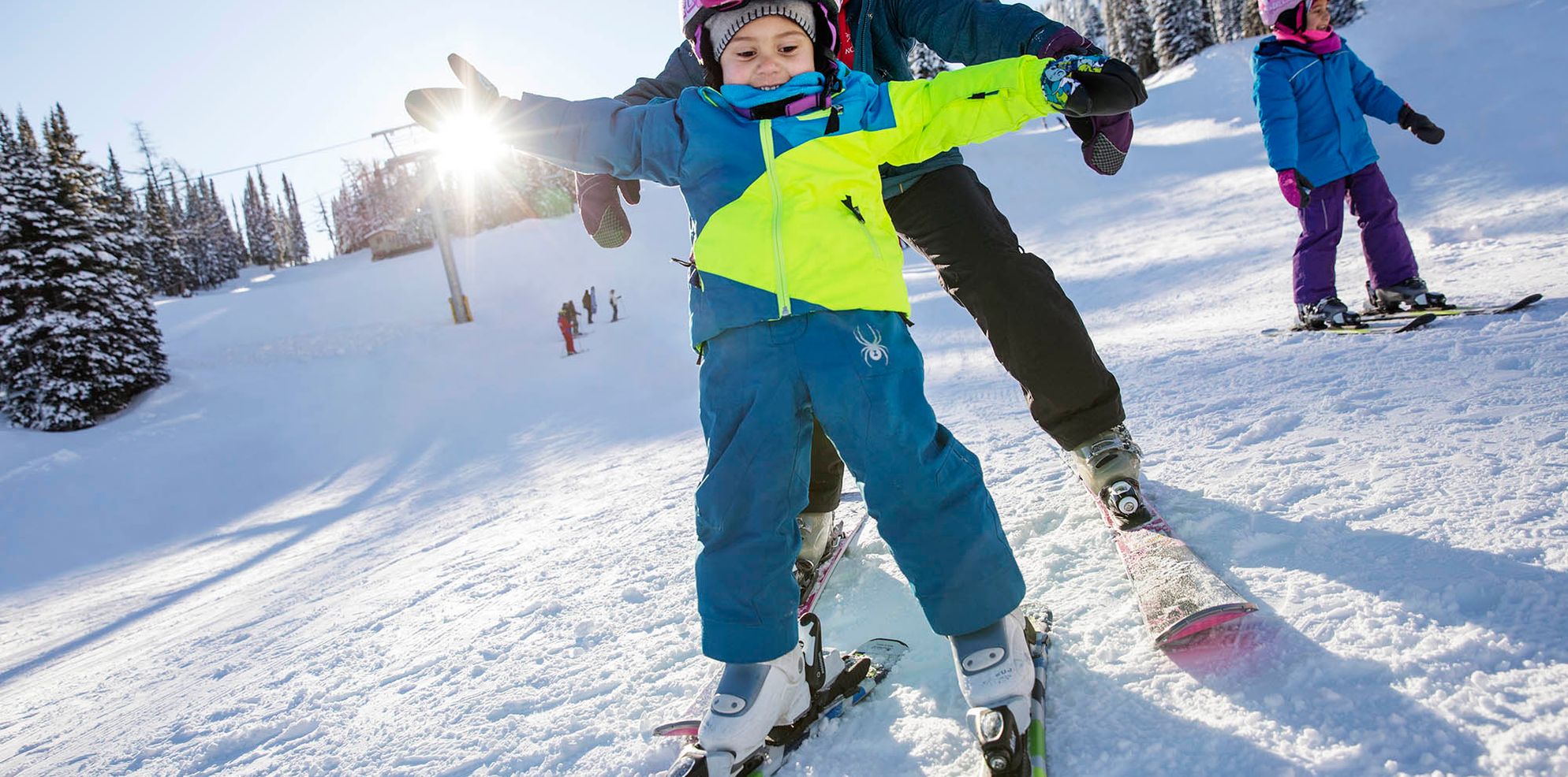 A little kid and their mom go downhill skiing at Banff Sunshine Village in Banff National Park.
