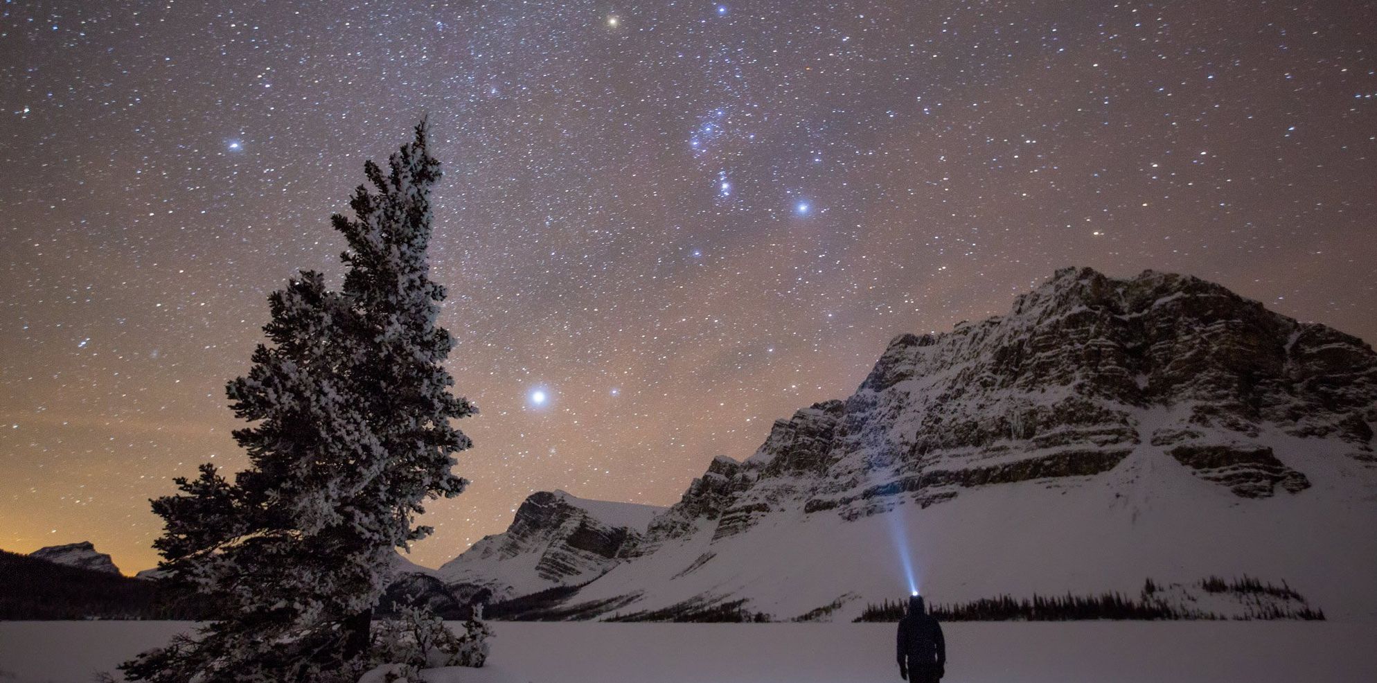 An onlooker takes in the outstandingly clear night skies of Lake Num Ti Jah, just off the Icefields Parkway in Banff National Park, AB.