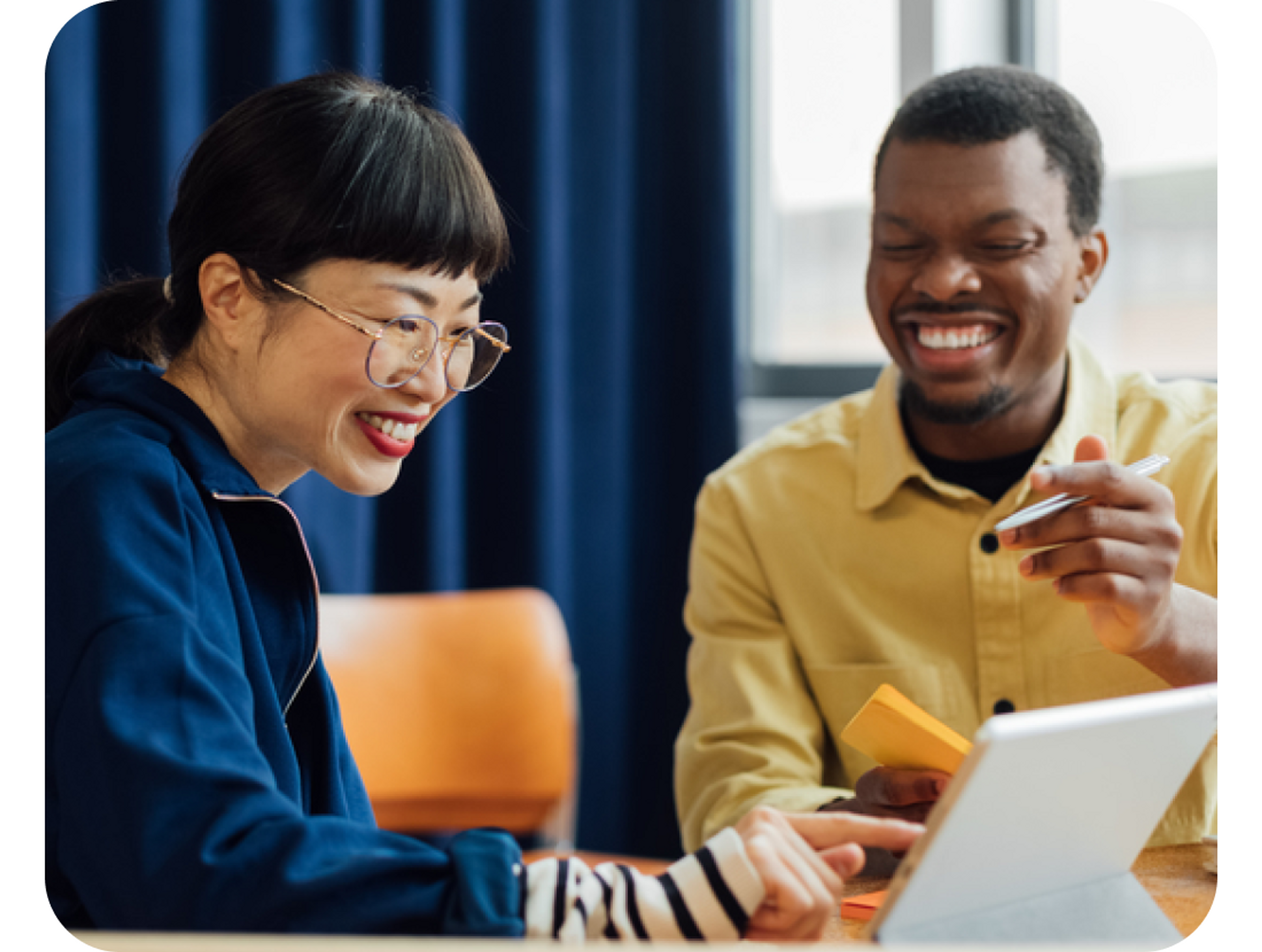 A photo of a man and woman smiling while looking at a laptop