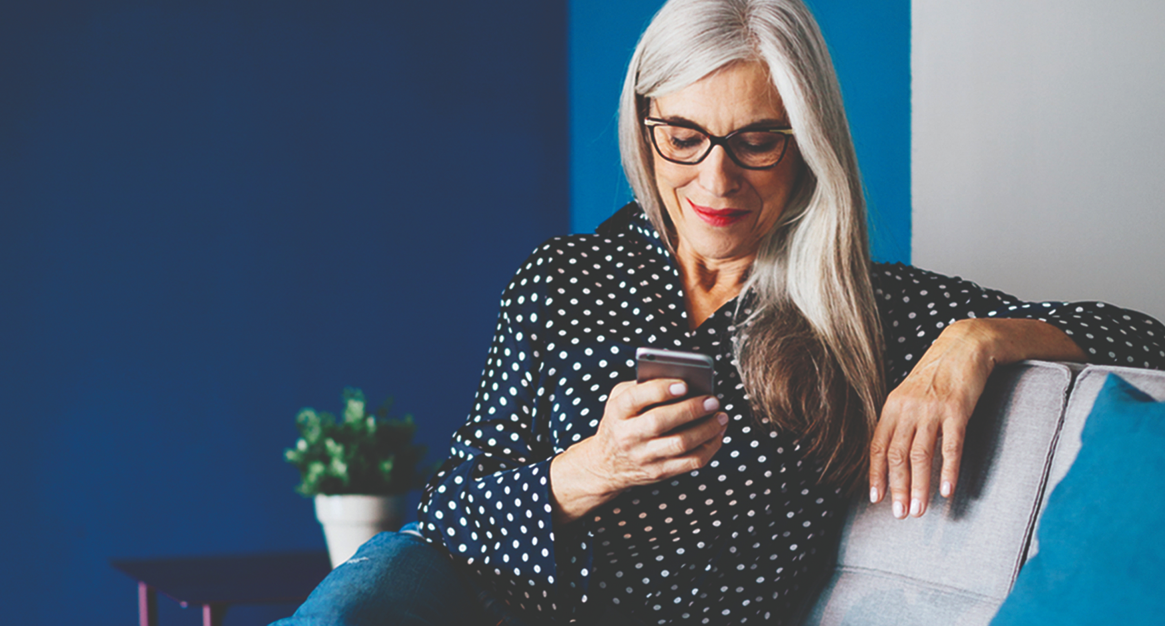 A photo of a woman looking at a phone while sat on a sofa