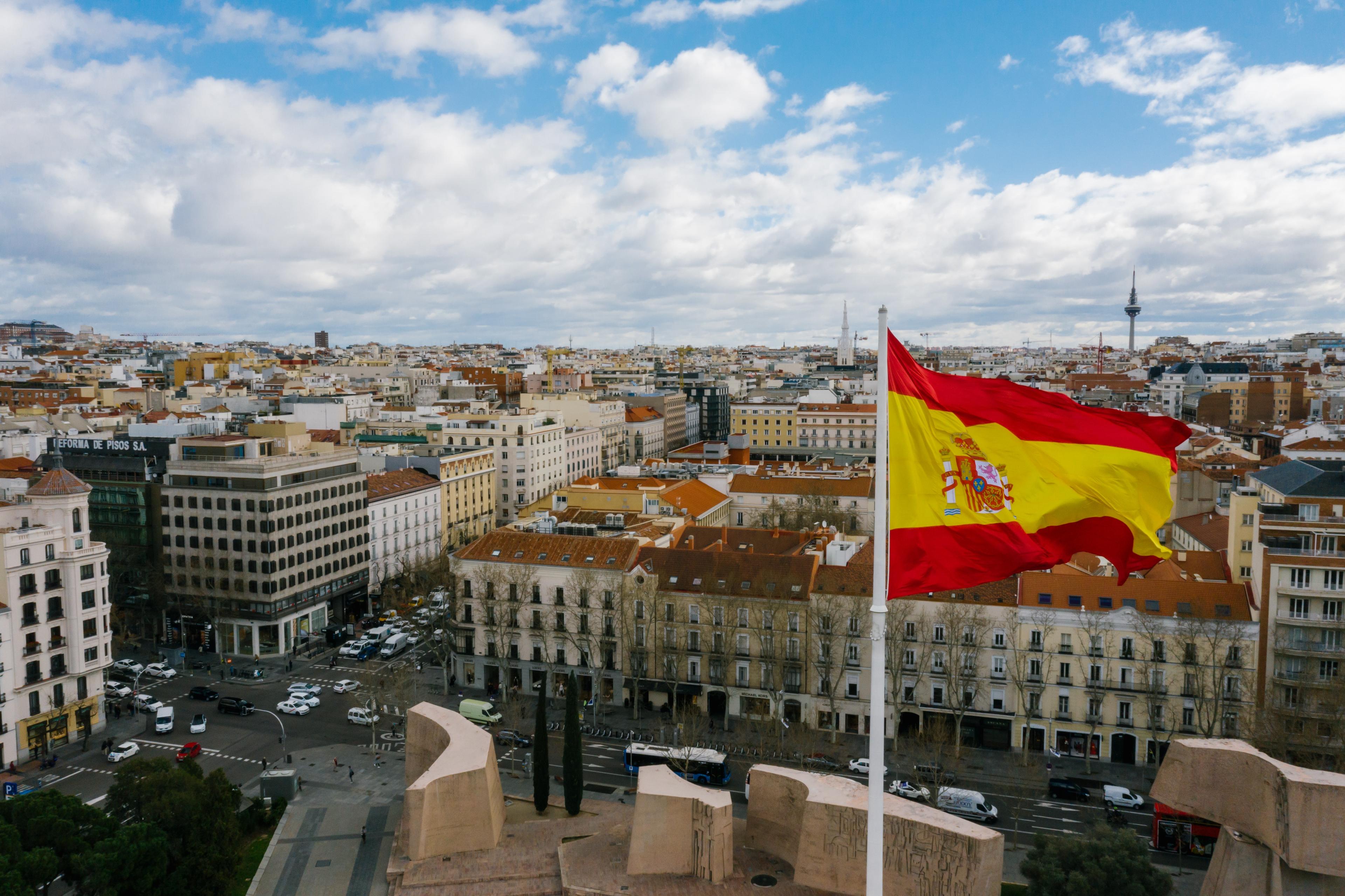 city scape of spain with a spanish flag in the foreground