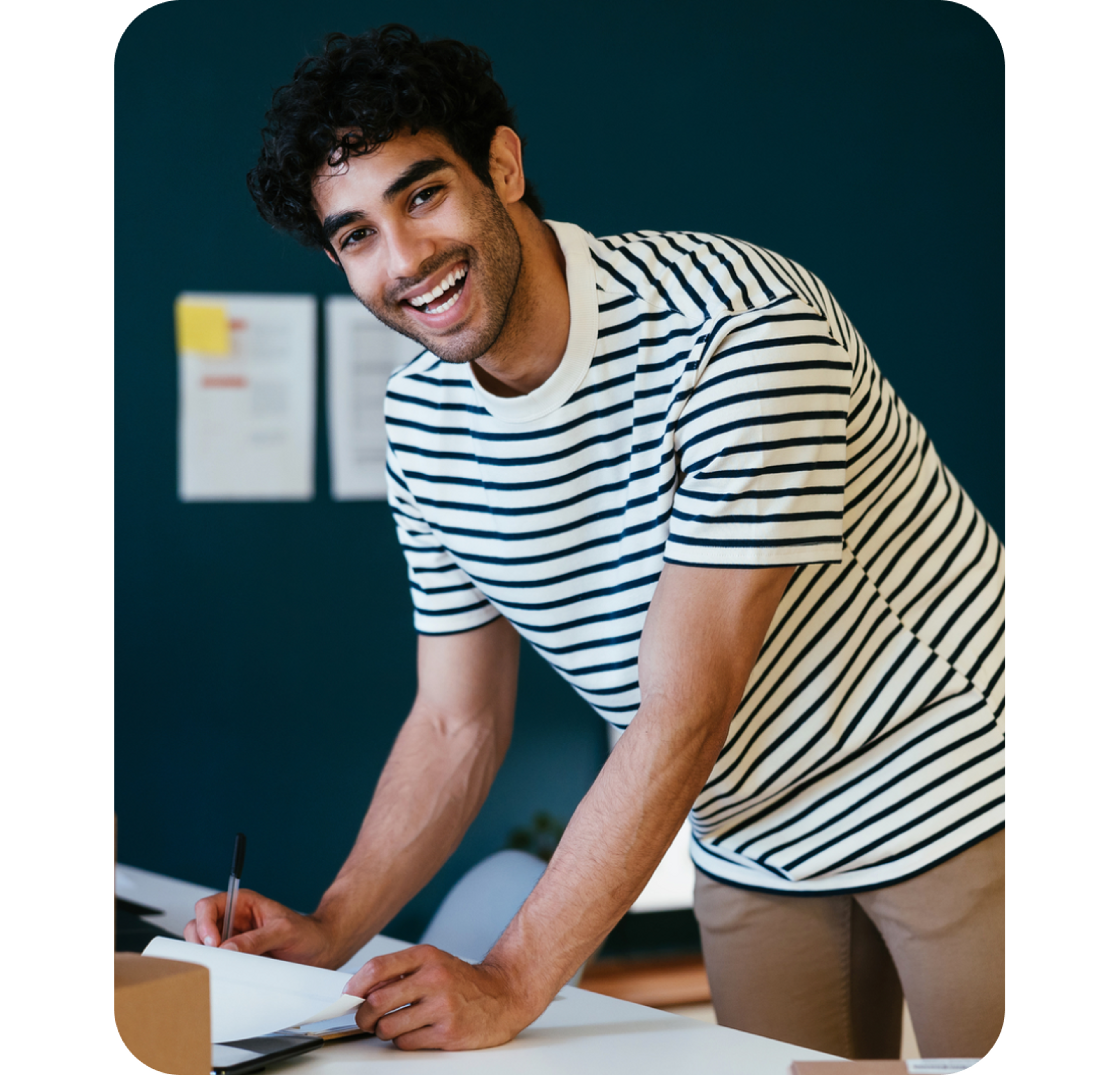 A photo of a smiling man sat standing over a desk