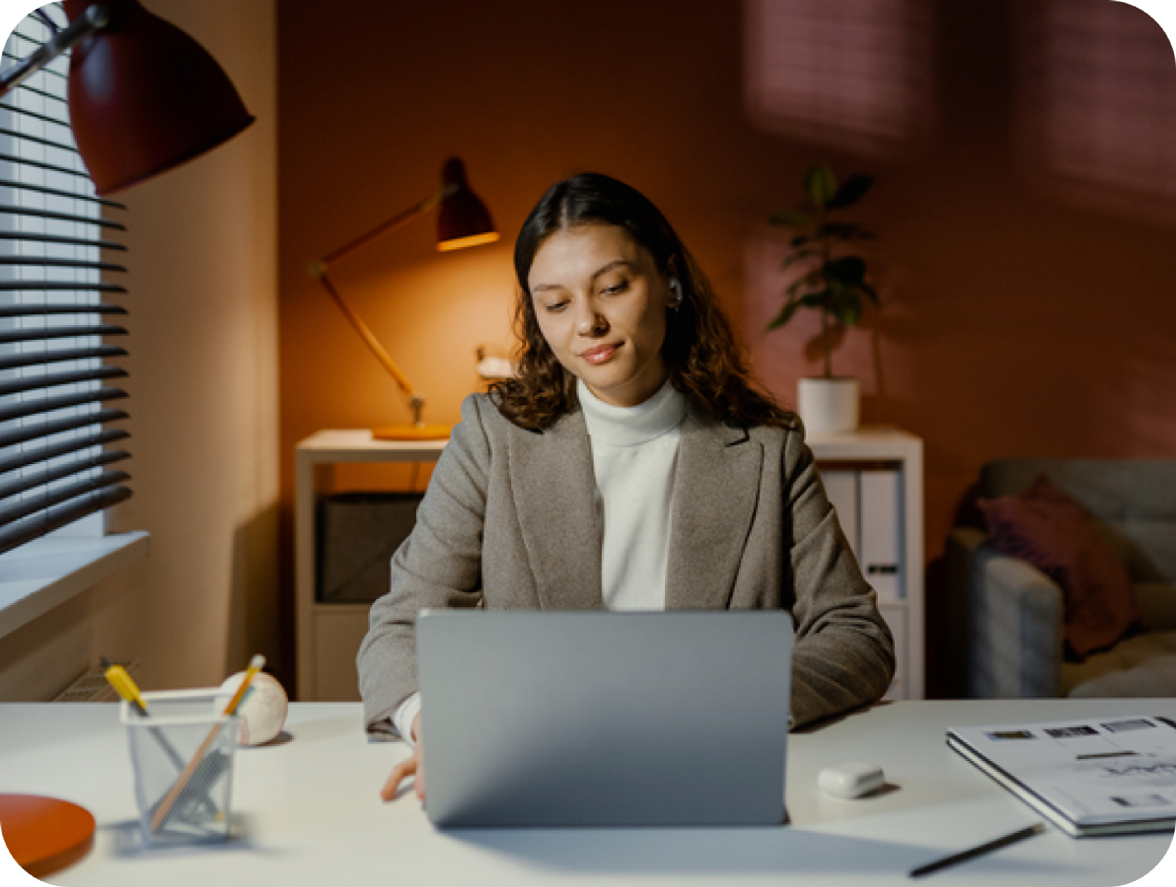 A photo of a woman looking down at a laptop in a home office environment