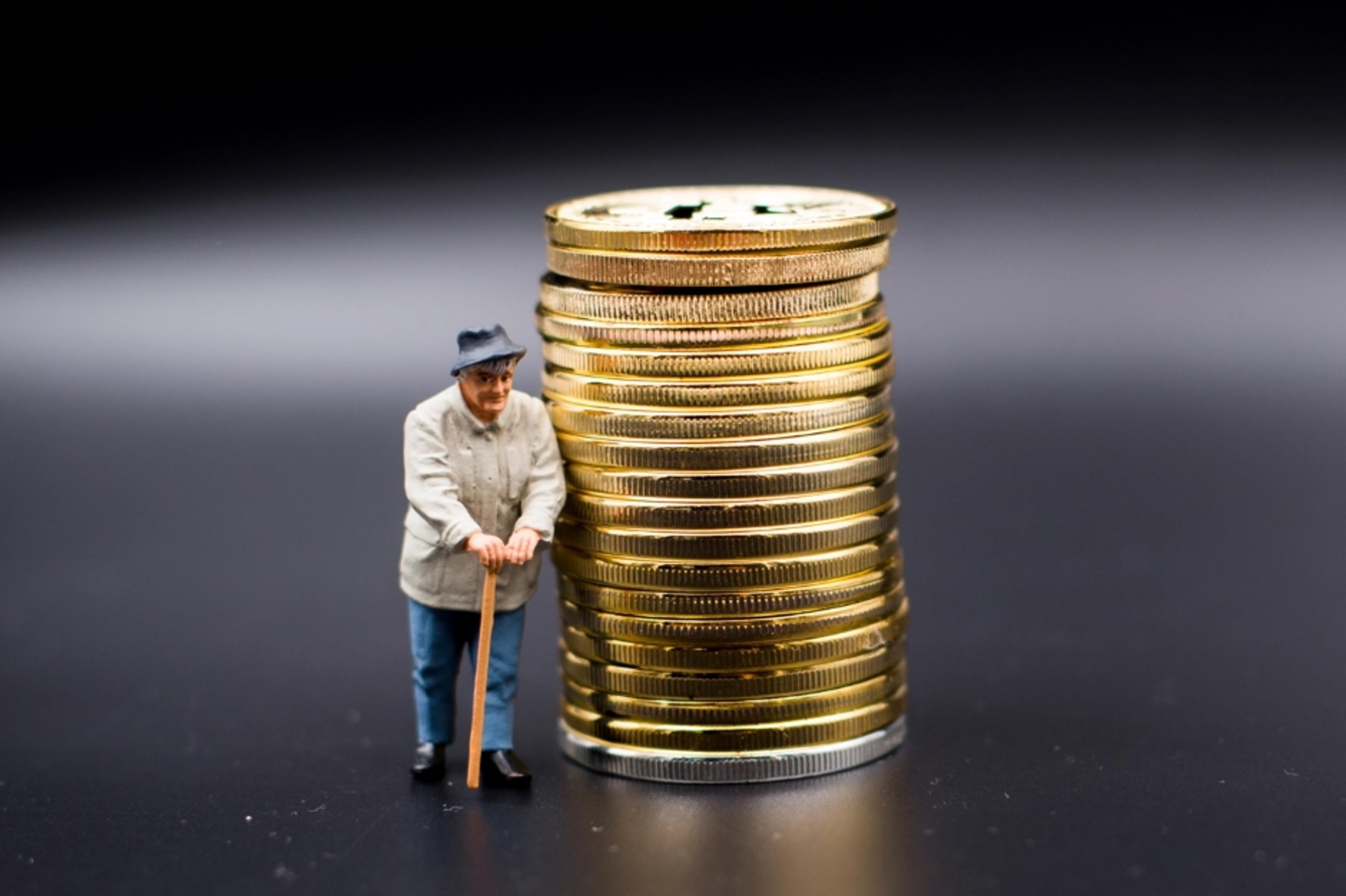 A photo of a miniature man standing next to a pile of coins