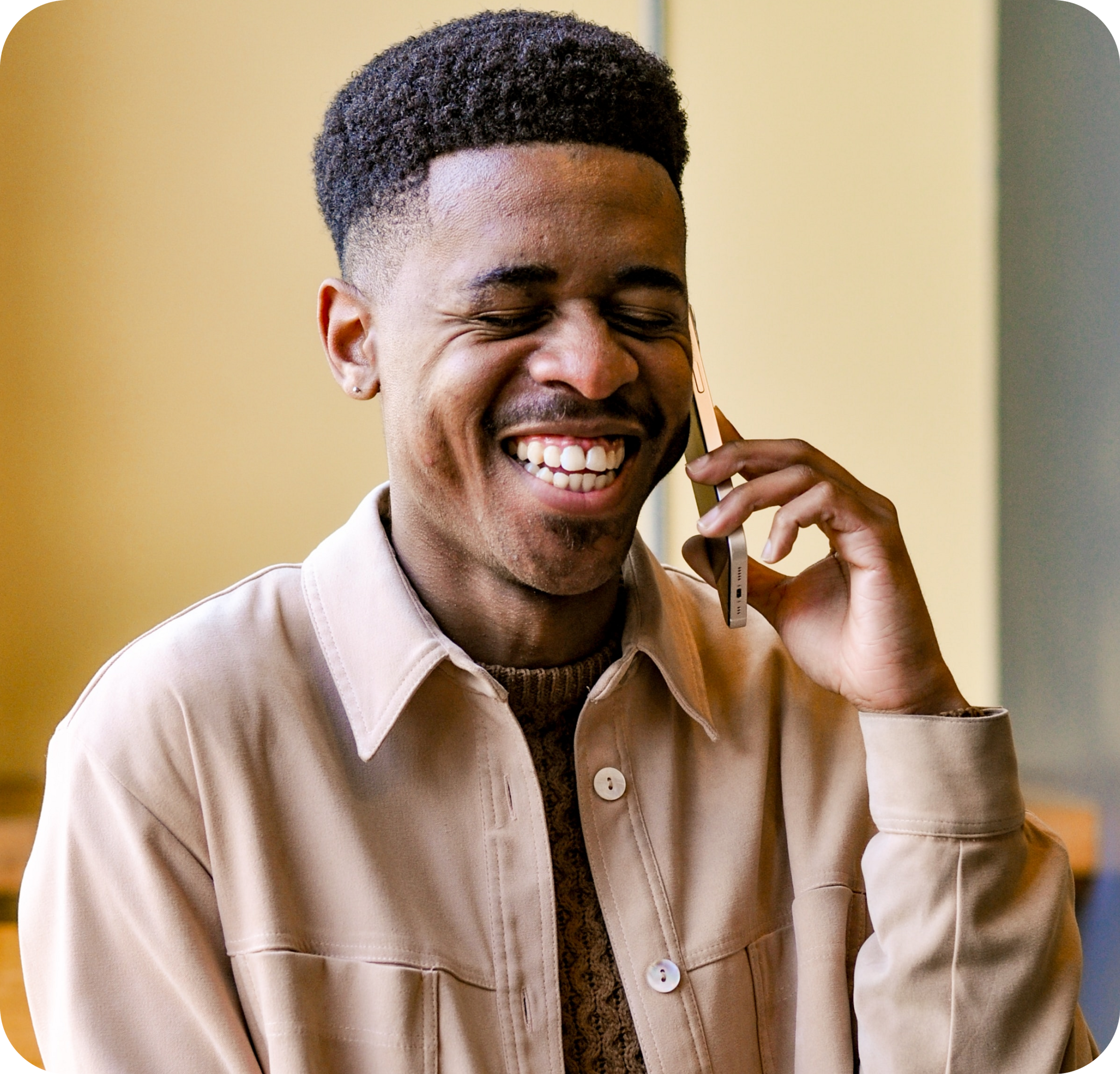A photo of a man laughing while speaking on a phone