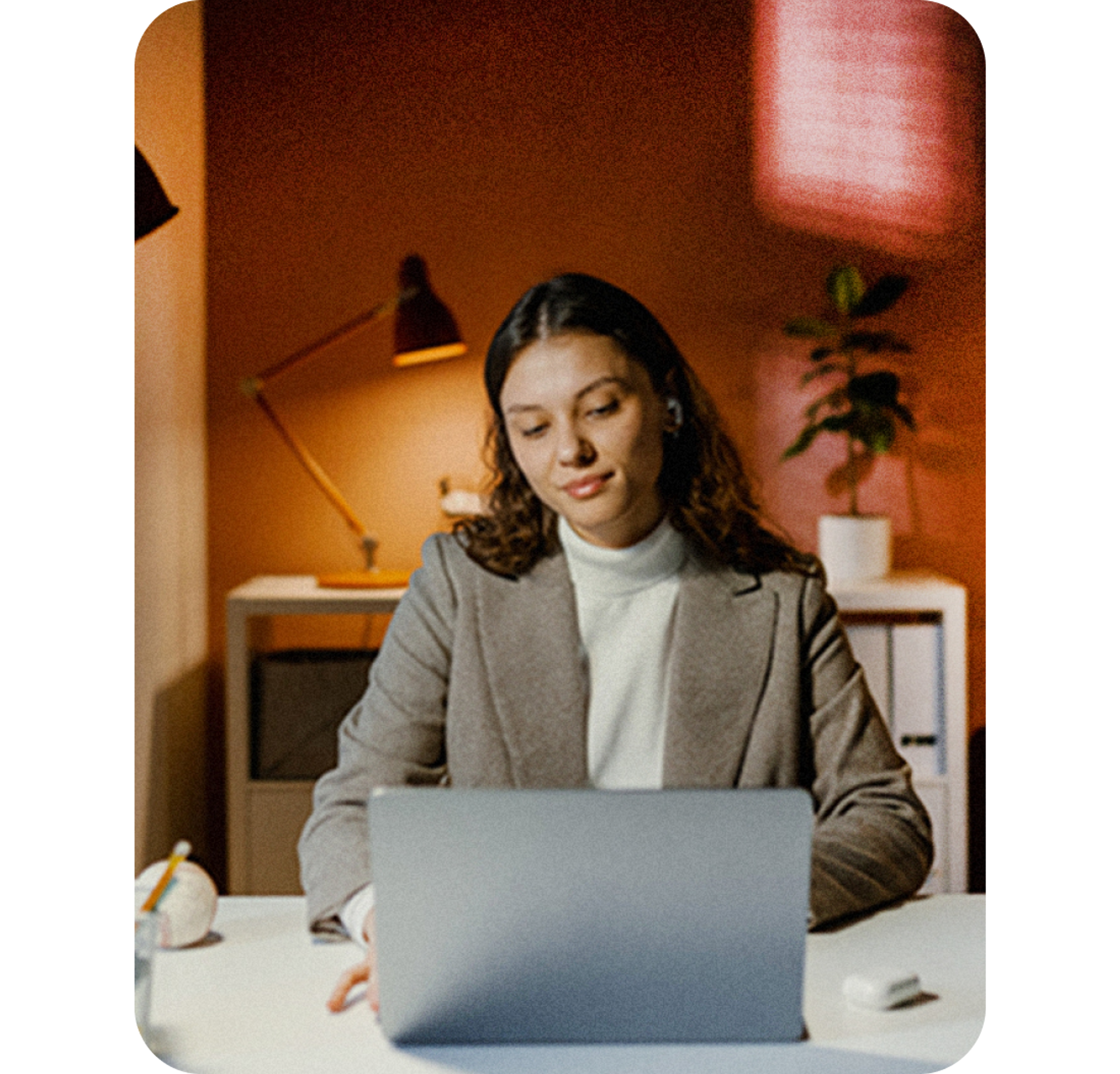 A photo of a woman smiling while looking at a laptop