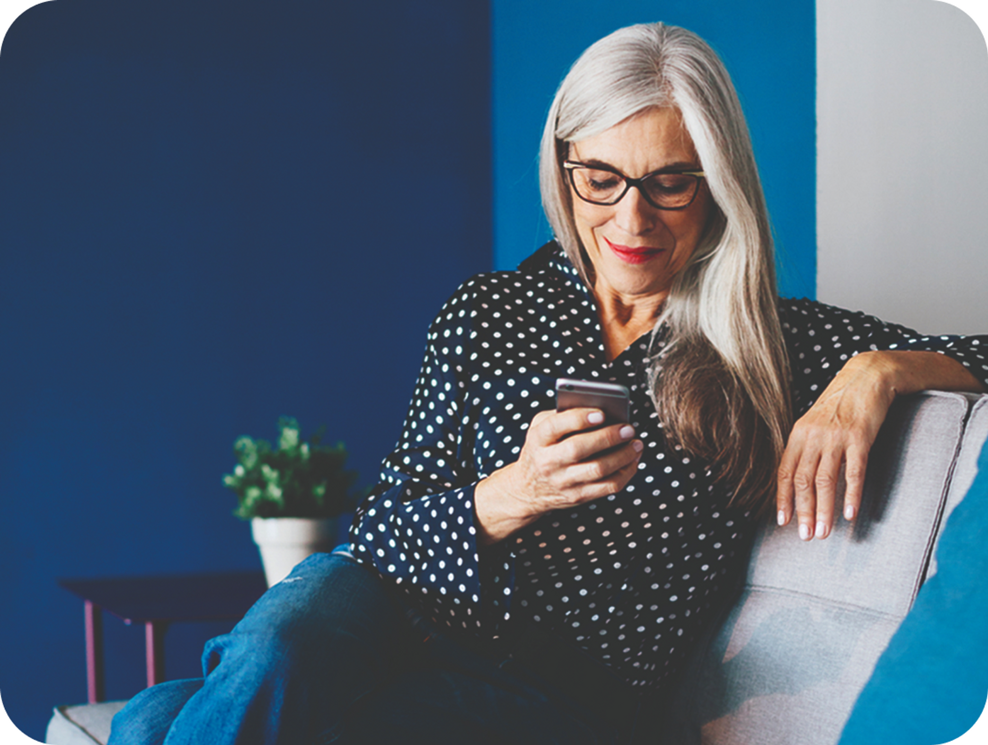 A photo of a woman sat on a sofa looking at her phone