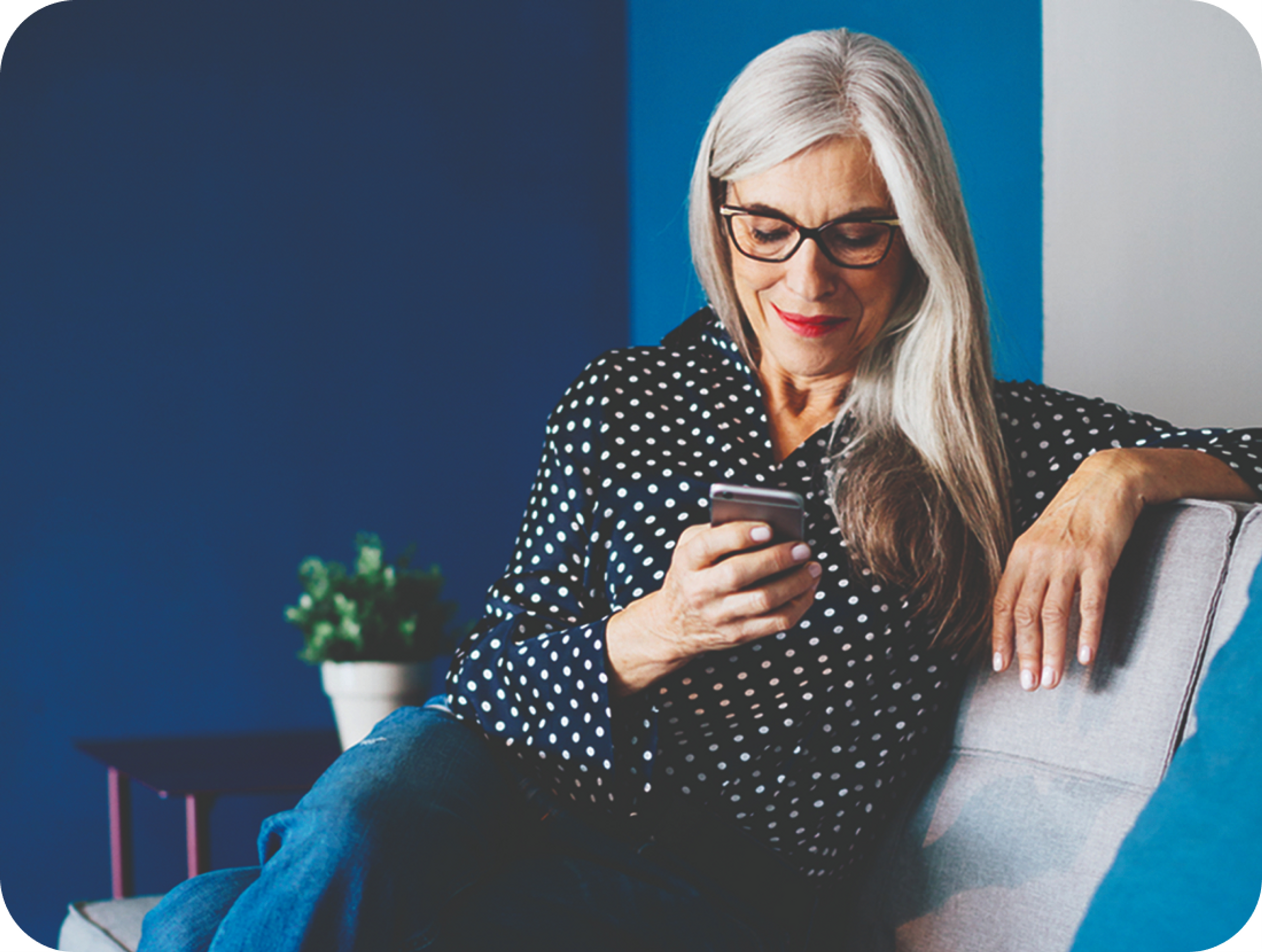 A photo of a woman looking at a phone while sat on a sofa