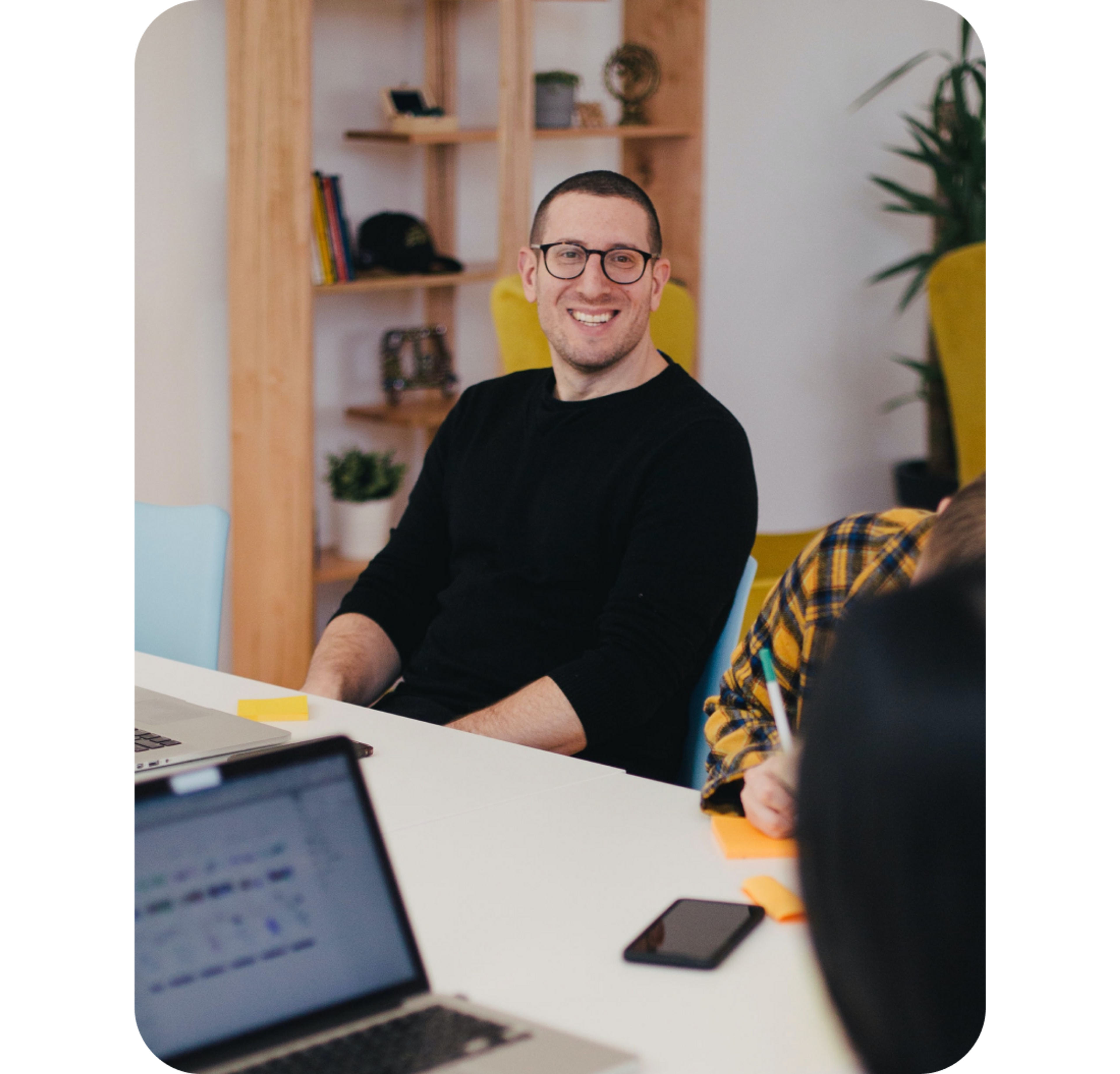 A photo of a man smiling while sat at a desk