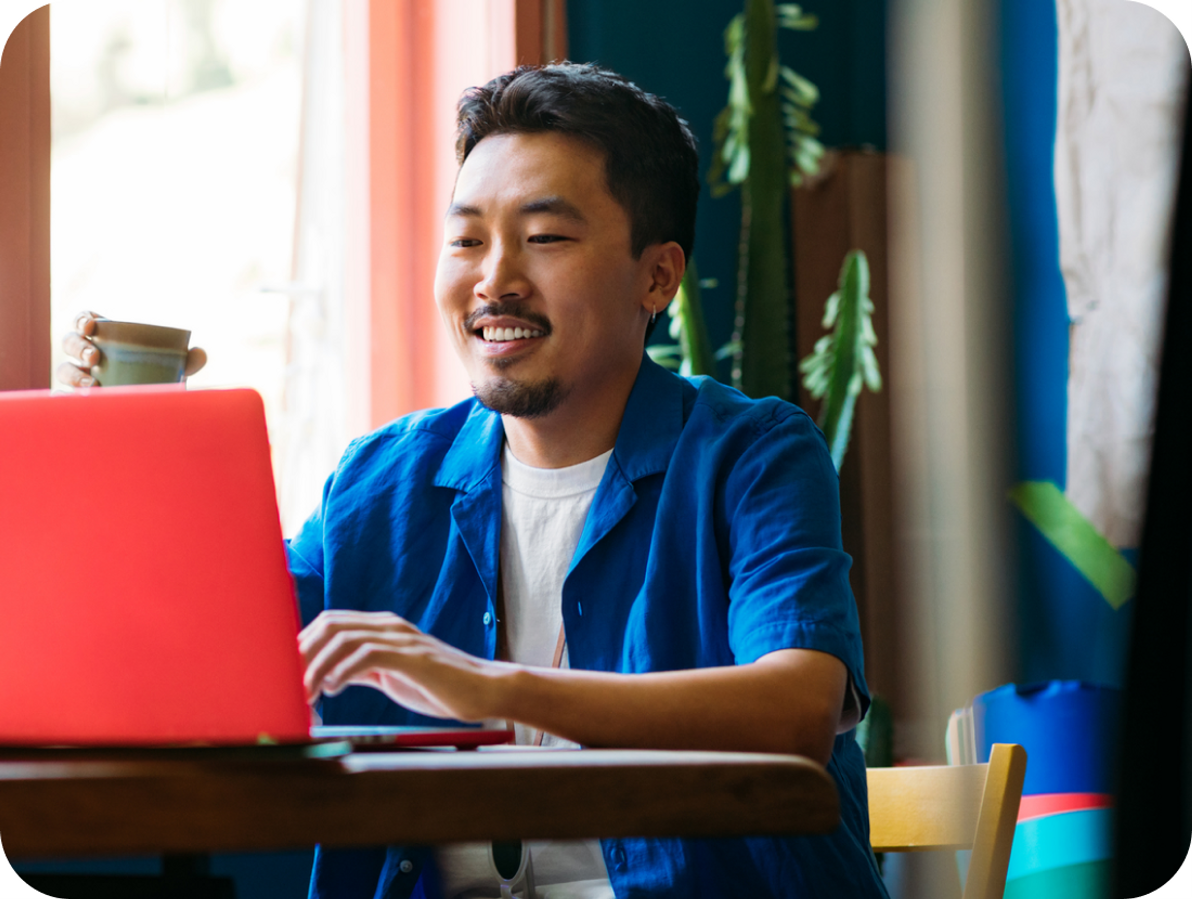 A photo of a man smiling and looking at a laptop