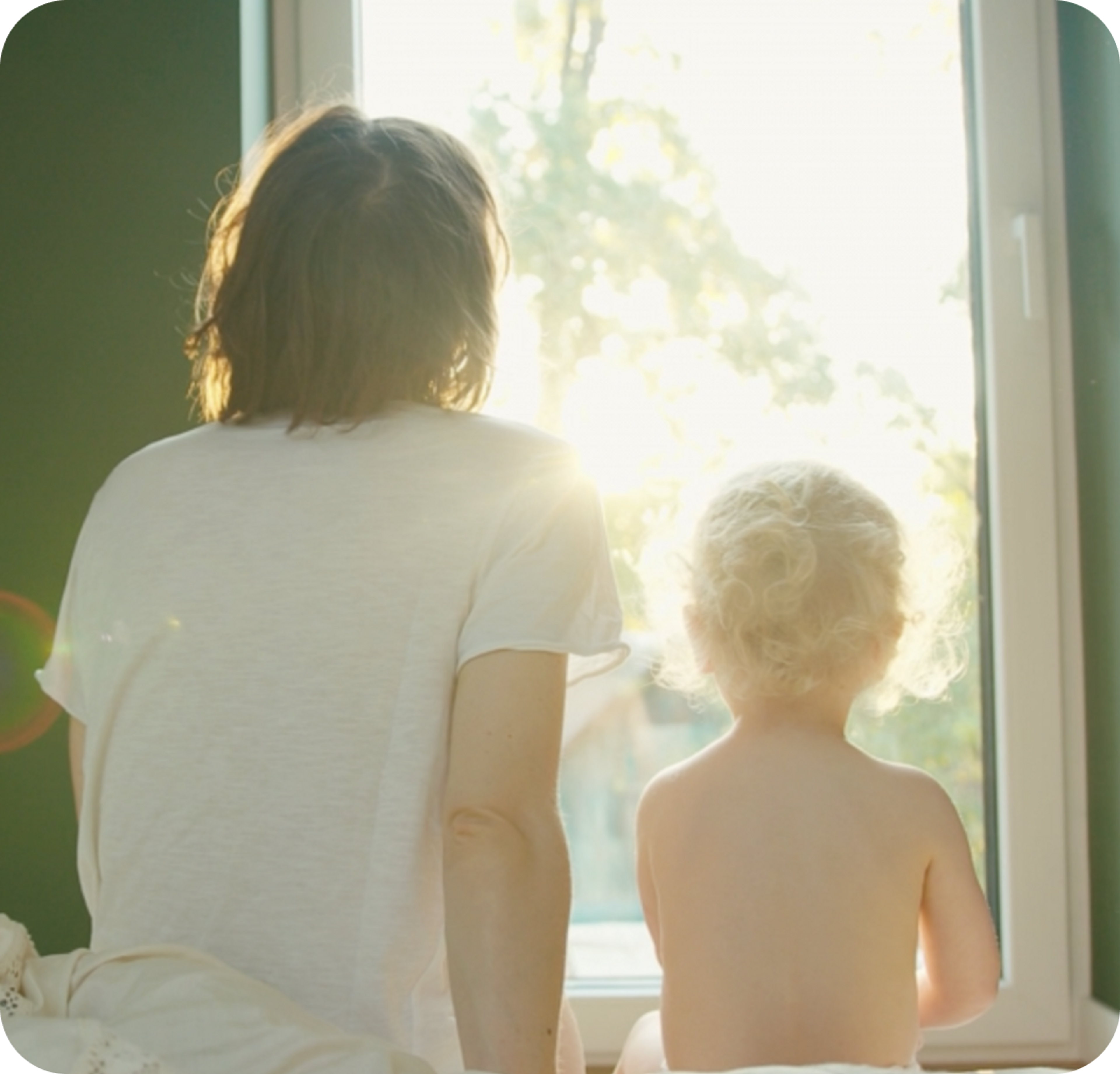 A photo of a woman and a young child looking out of a window