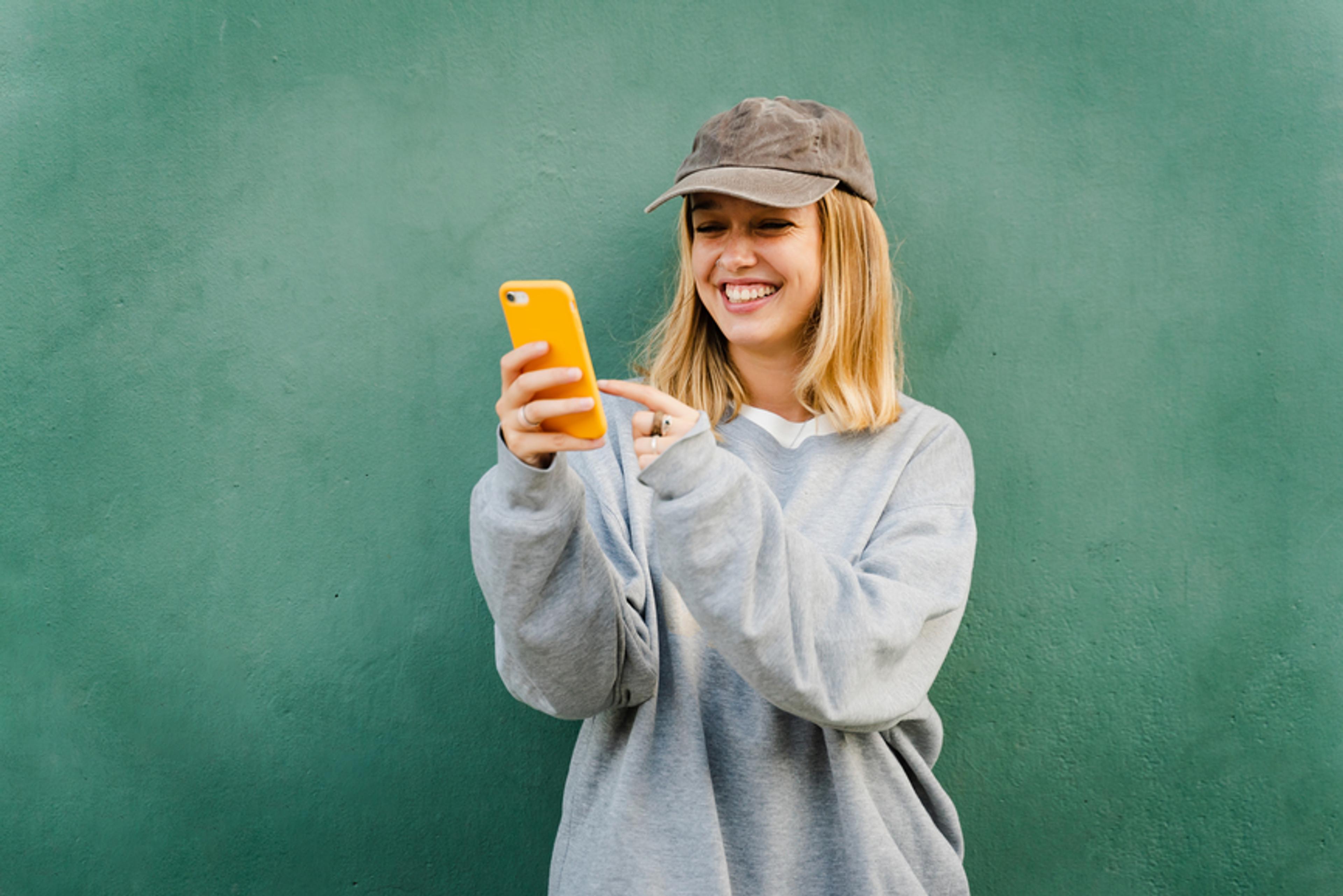 A photo of a woman smiling and looking at her phone