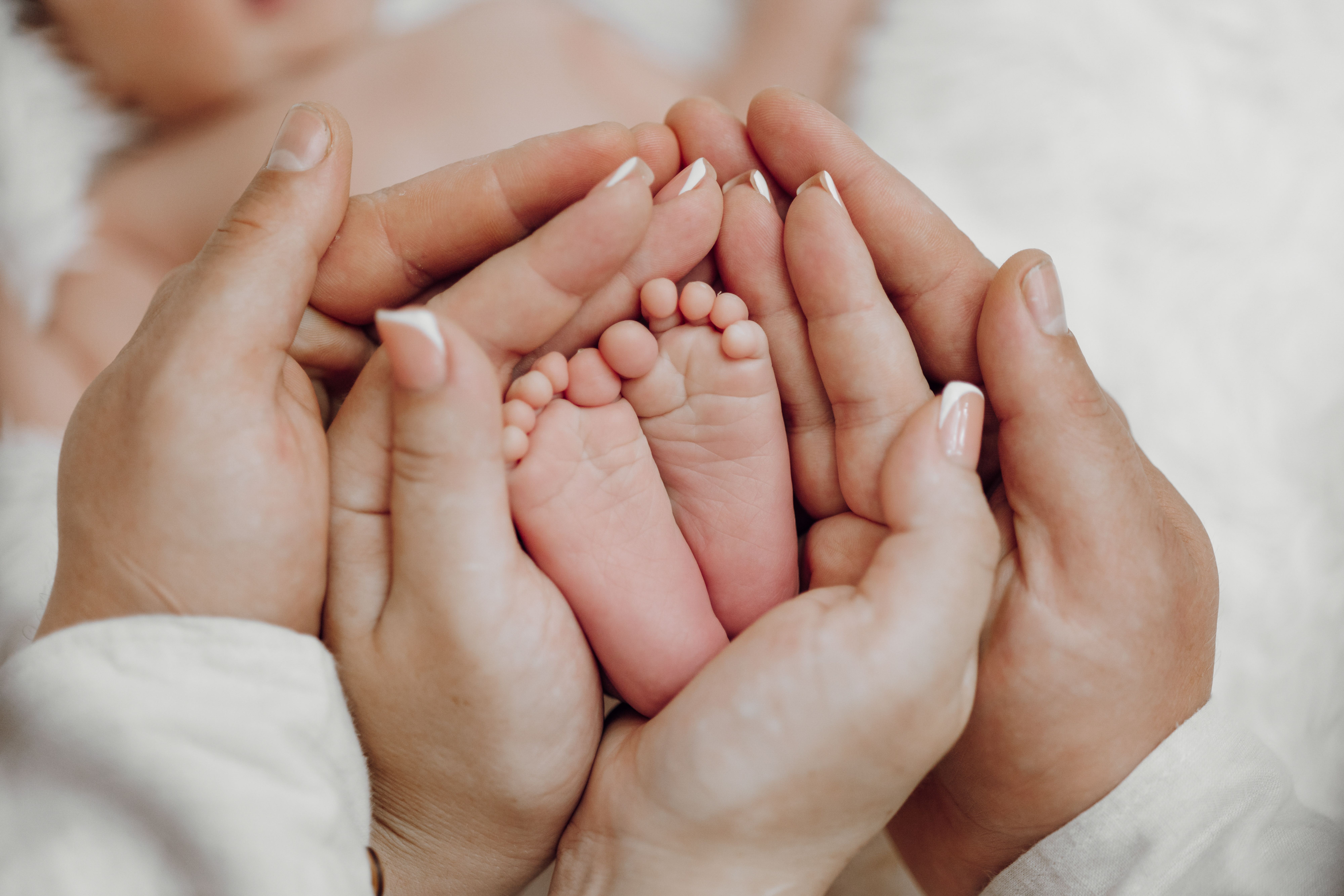 The baby’s feet in its parents’ hands
