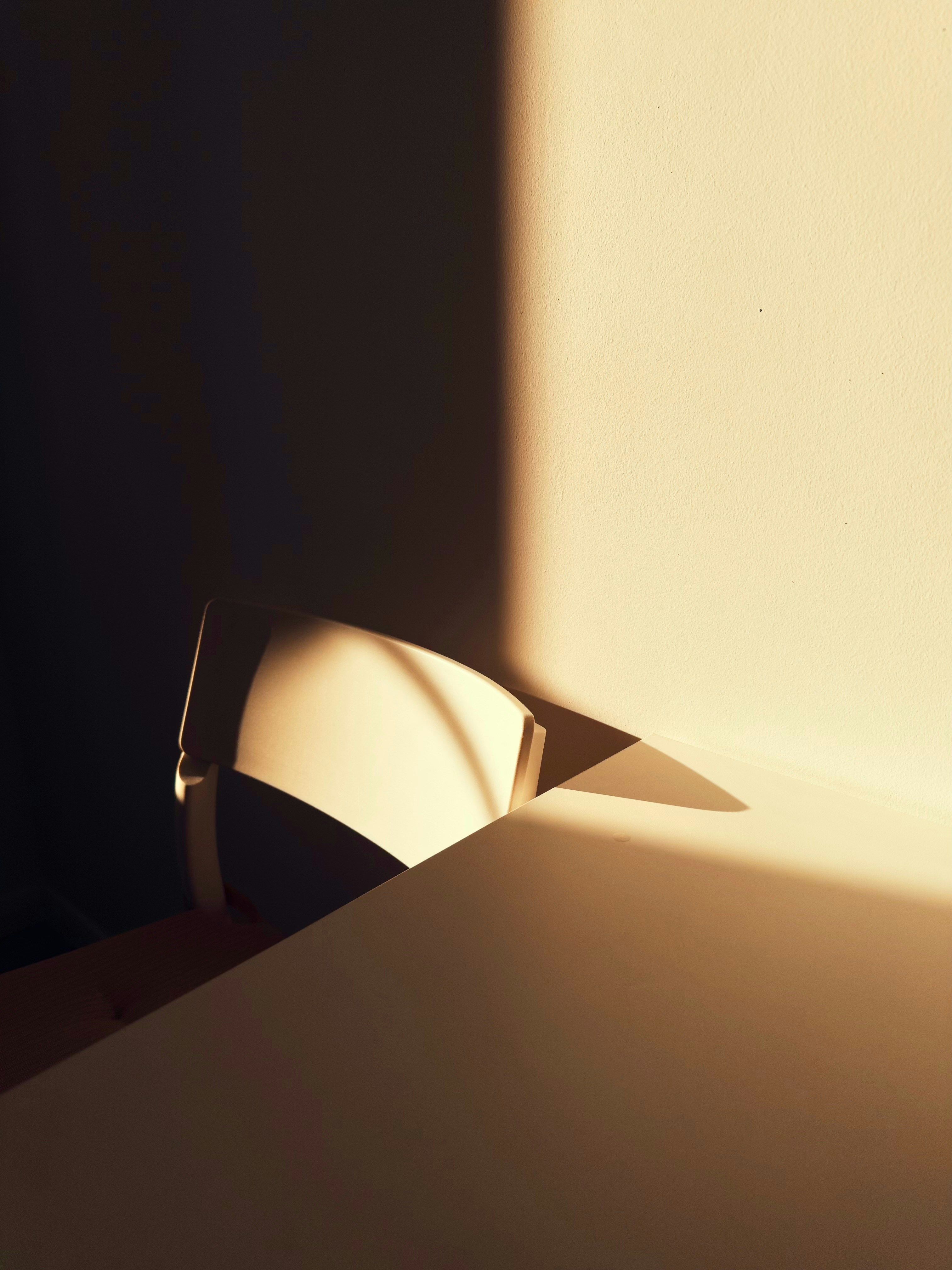 Chair next to a table, shadows falling from the left