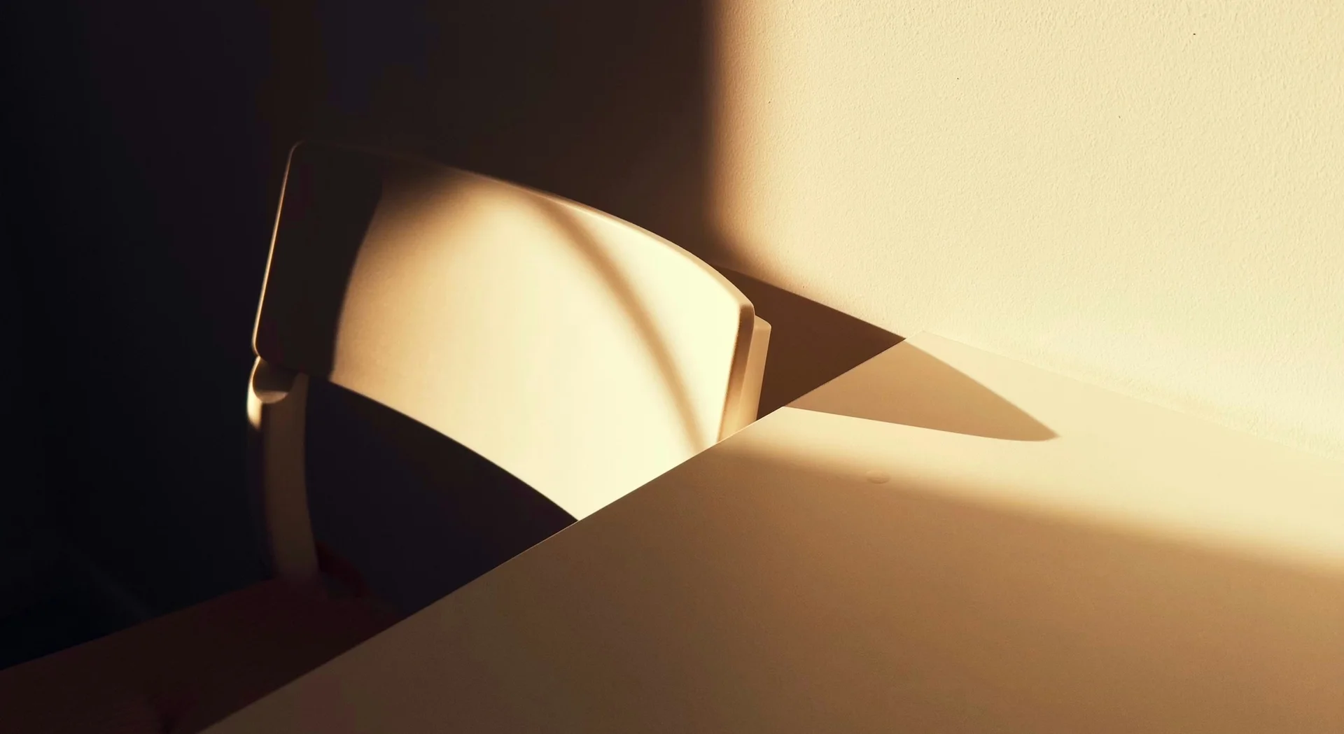 Chair next to a table, shadows falling from the left
