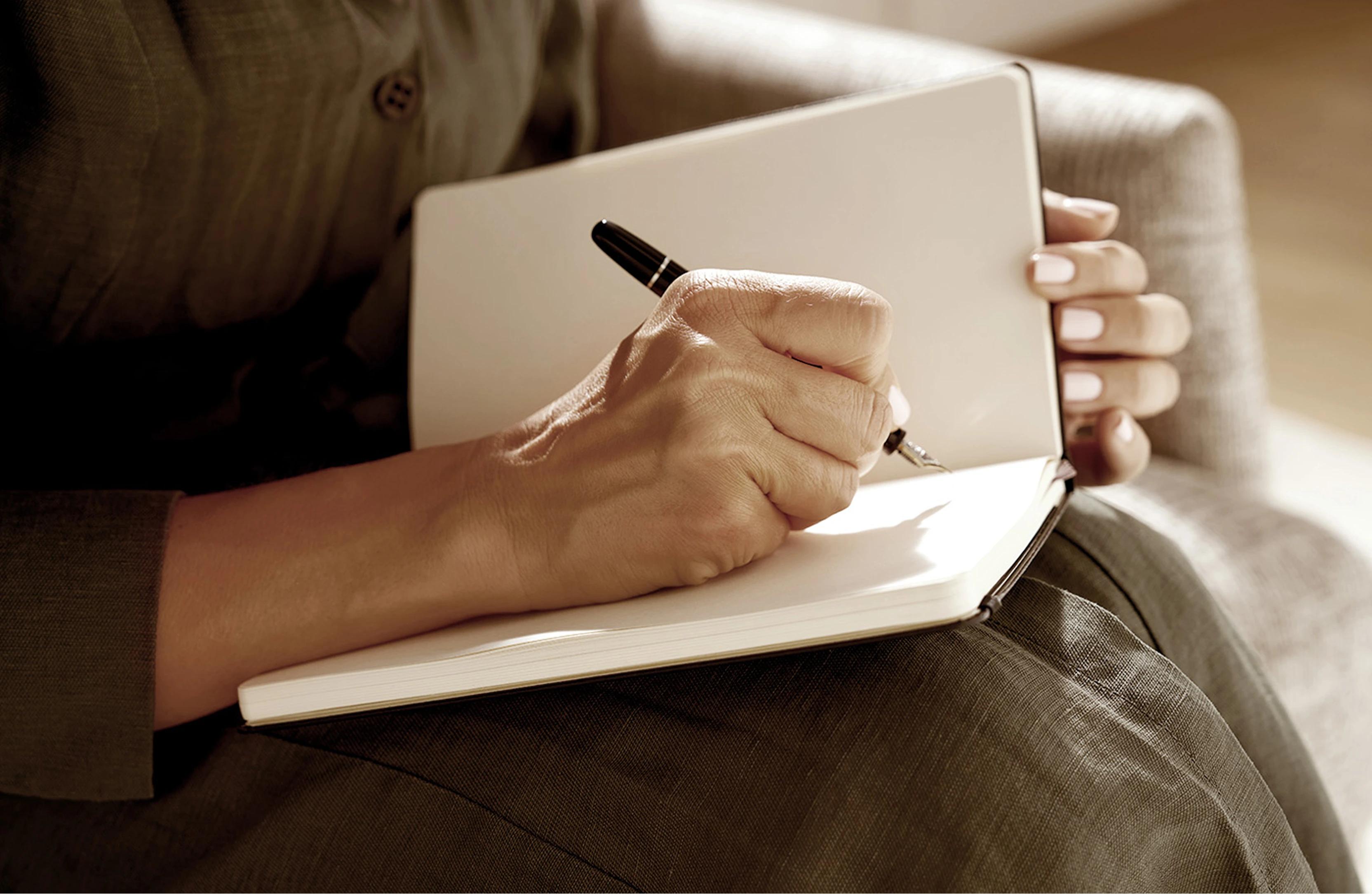 Person with pen writing on book 