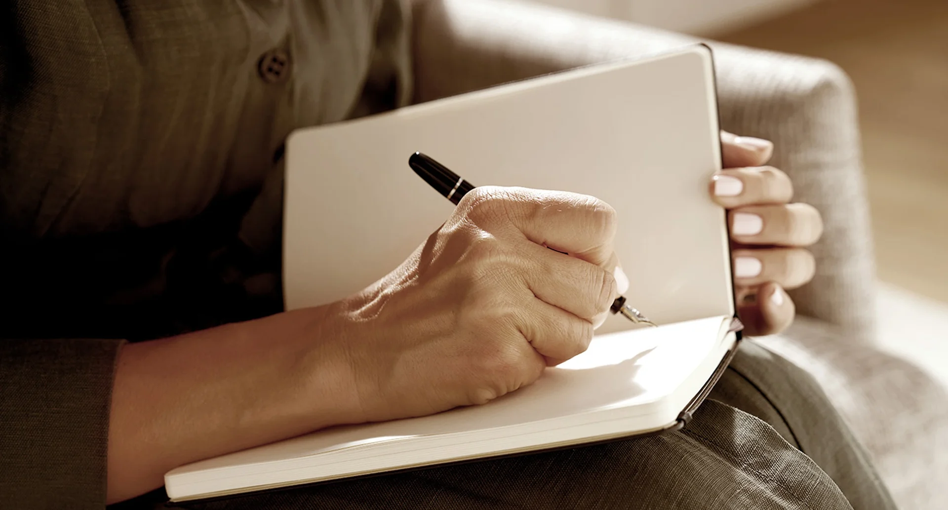 Person with pen writing on book