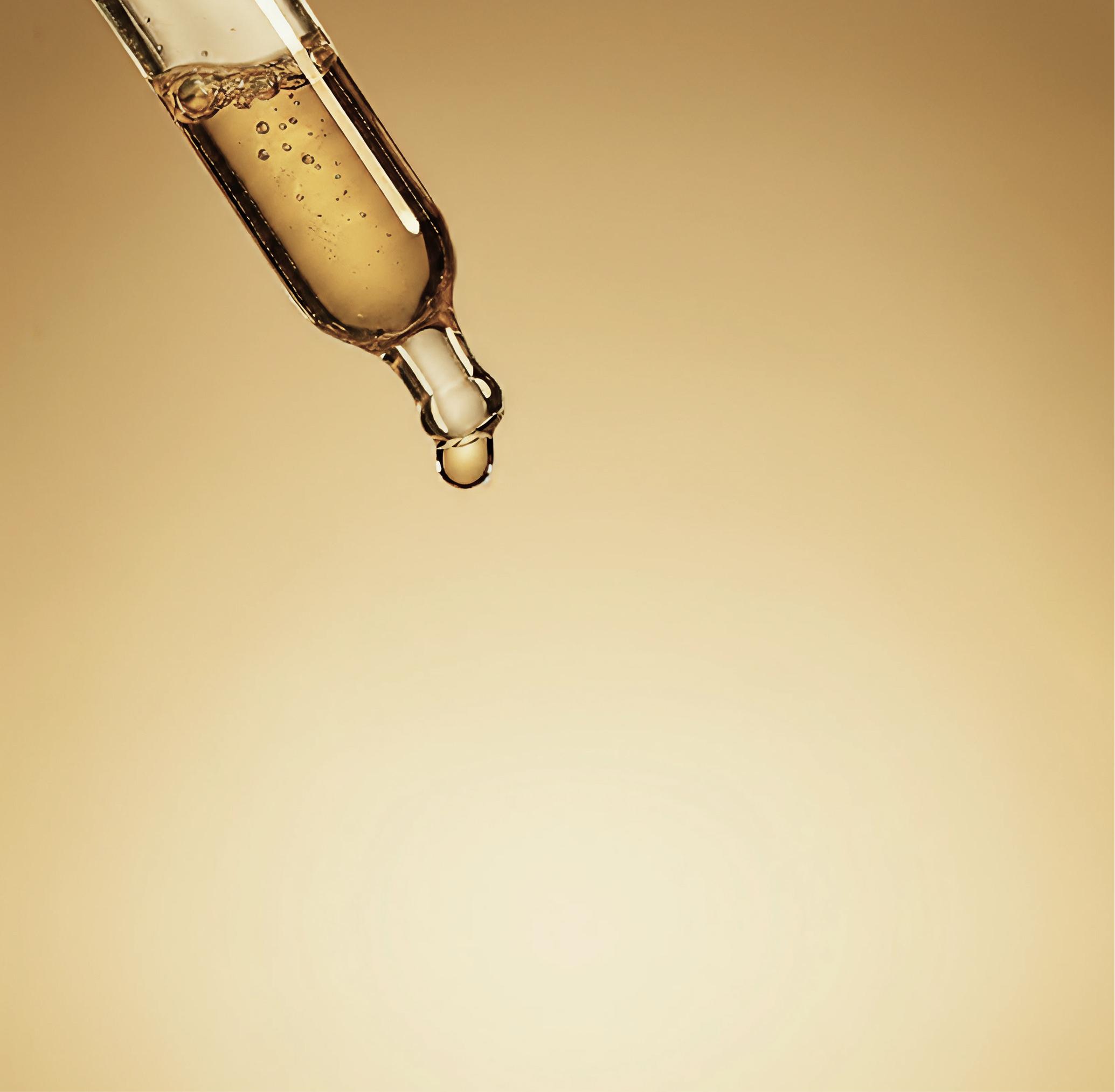 Golden liquid in a dropper with a single drop about to fall.