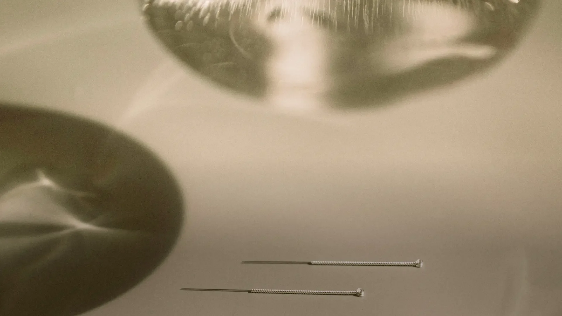 Acupuncture needles on a reflective surface.