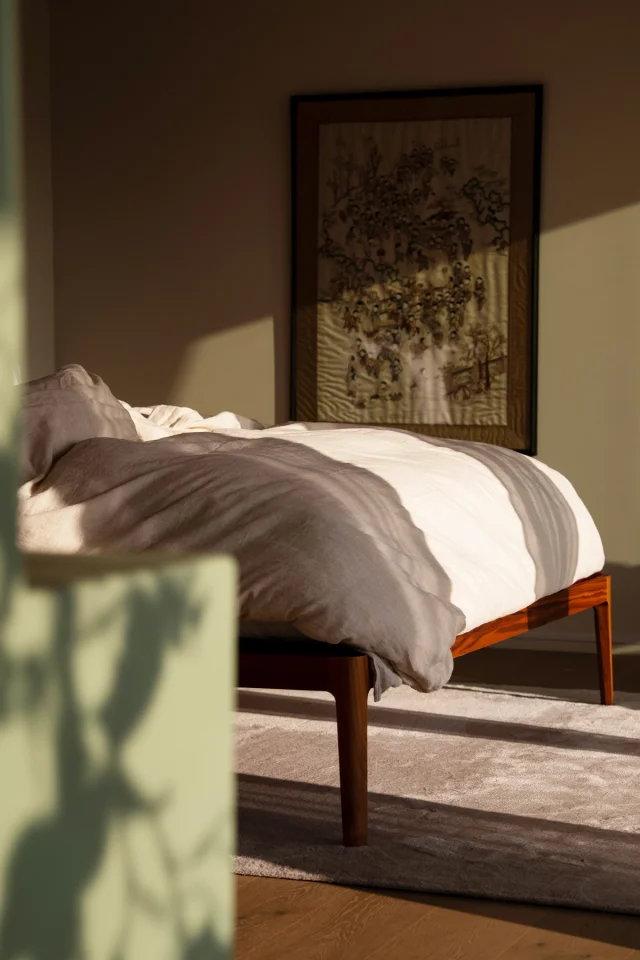 Cozy bed with patterned shadows falling across it