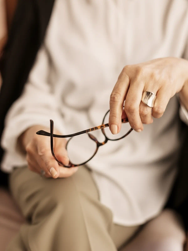 Discover our approach - someone sitting on a chair holding a pair of glasses in the kusnacht practice