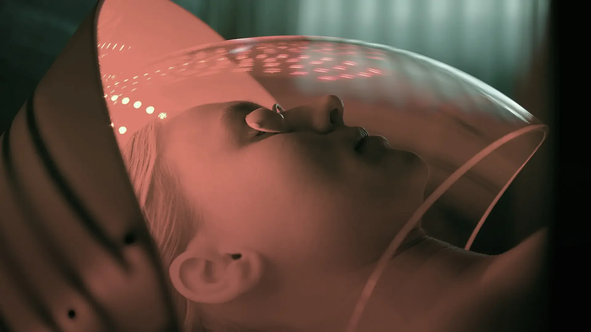 Longevity & Mental Health: A Holistic Connection. Close-up of an individual undergoing red light therapy, with their head partially enclosed in a clear, luminous dome.