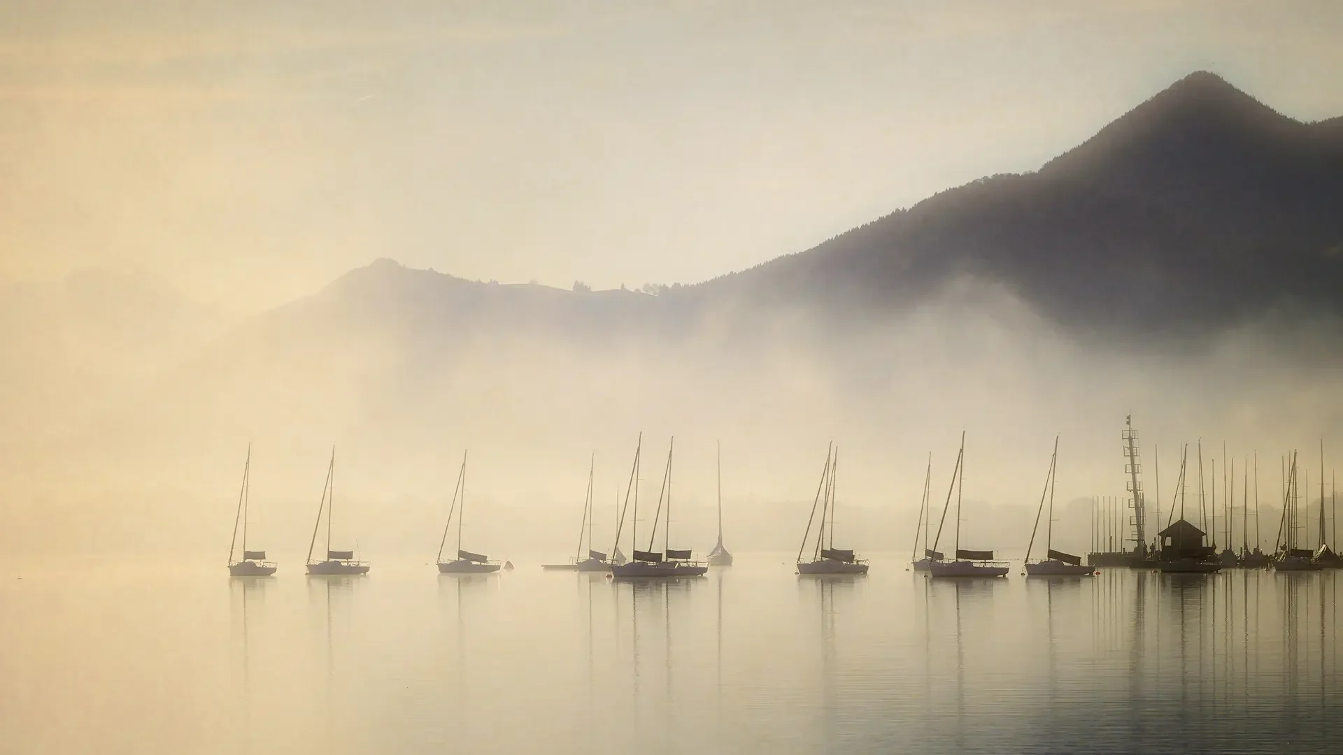 View of a lake with floating boats in the misty morning light