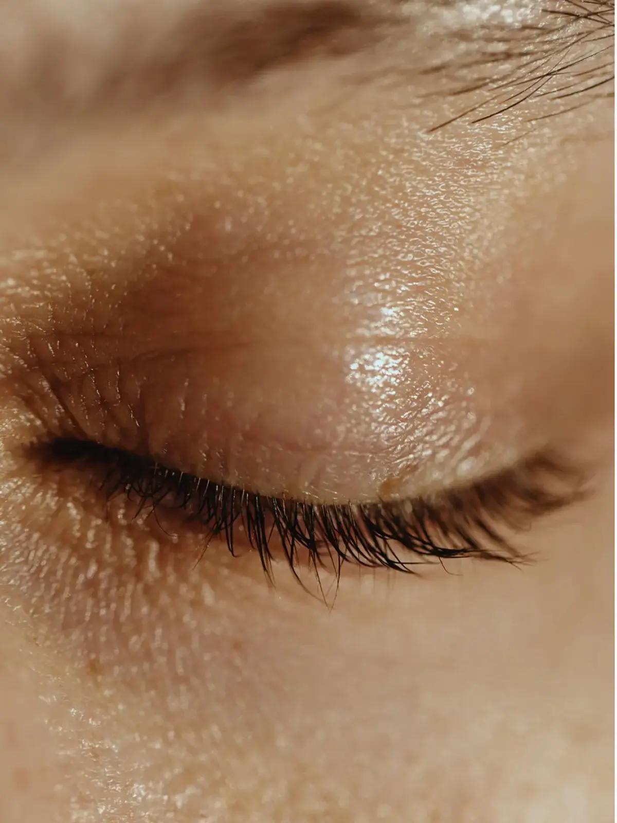 Close-up of a closed eye with visible eyelashes and skin texture.
