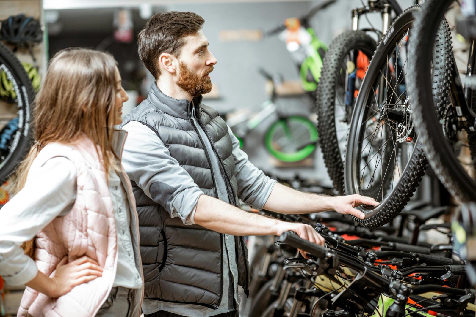 Bike shop staff member talking a customer through a bike on the shop floor