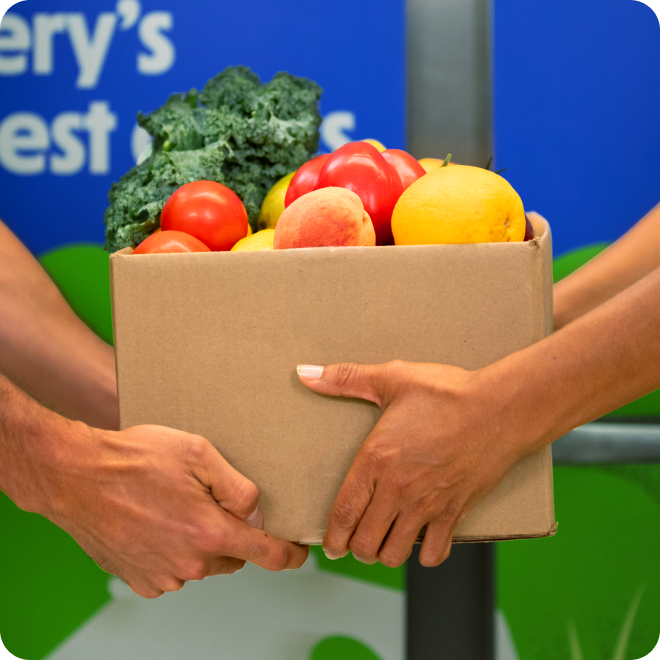store employee handing over produce box to customer