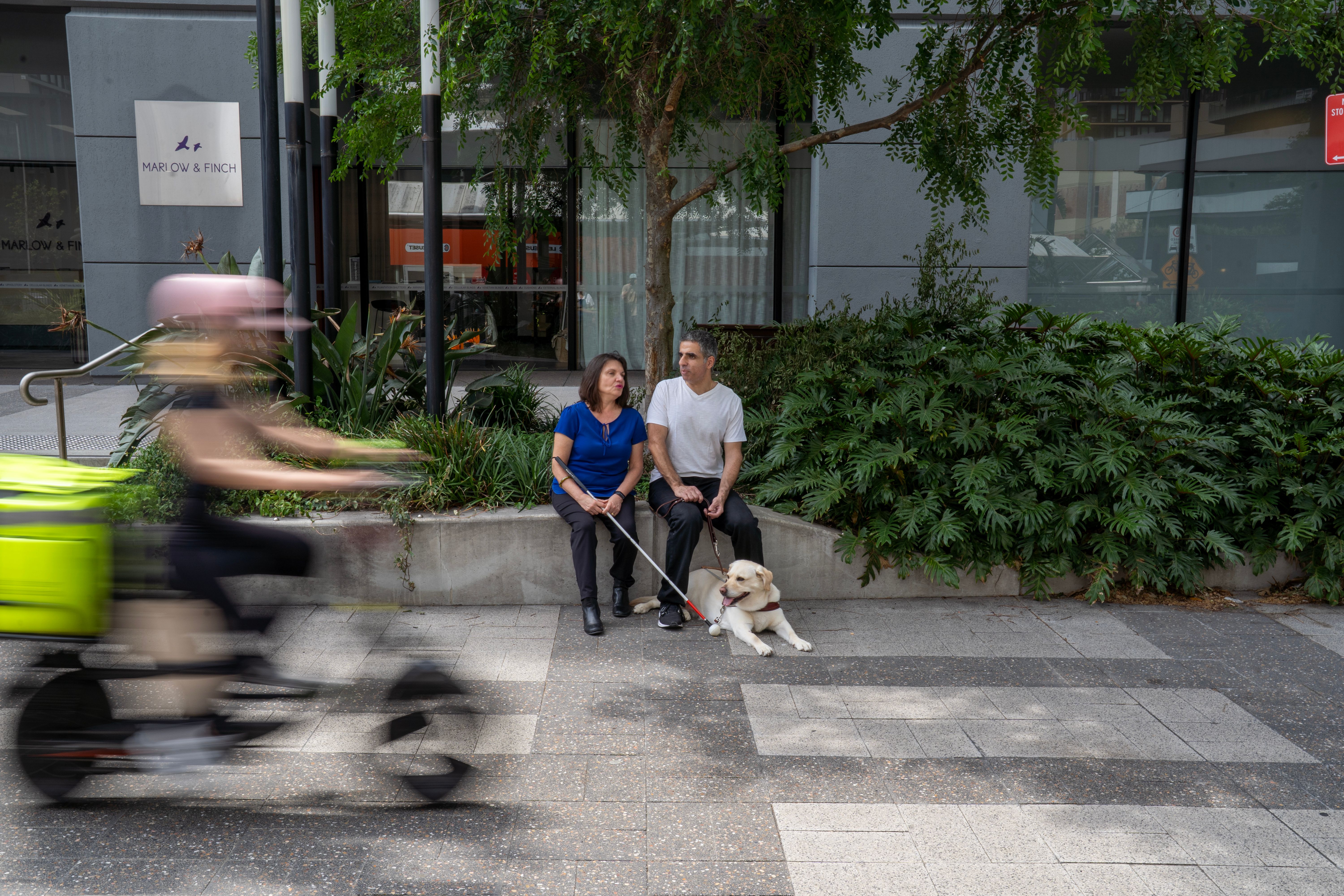 Two people sitting down with a scooter going past them.