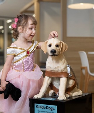 A girl putting a coin in a donation dog.