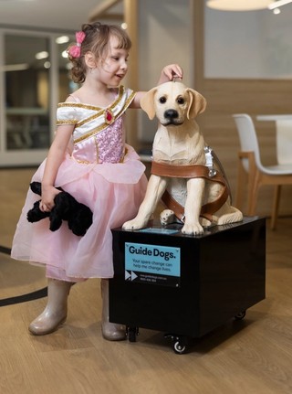 A girl putting a coin in a donation dog.