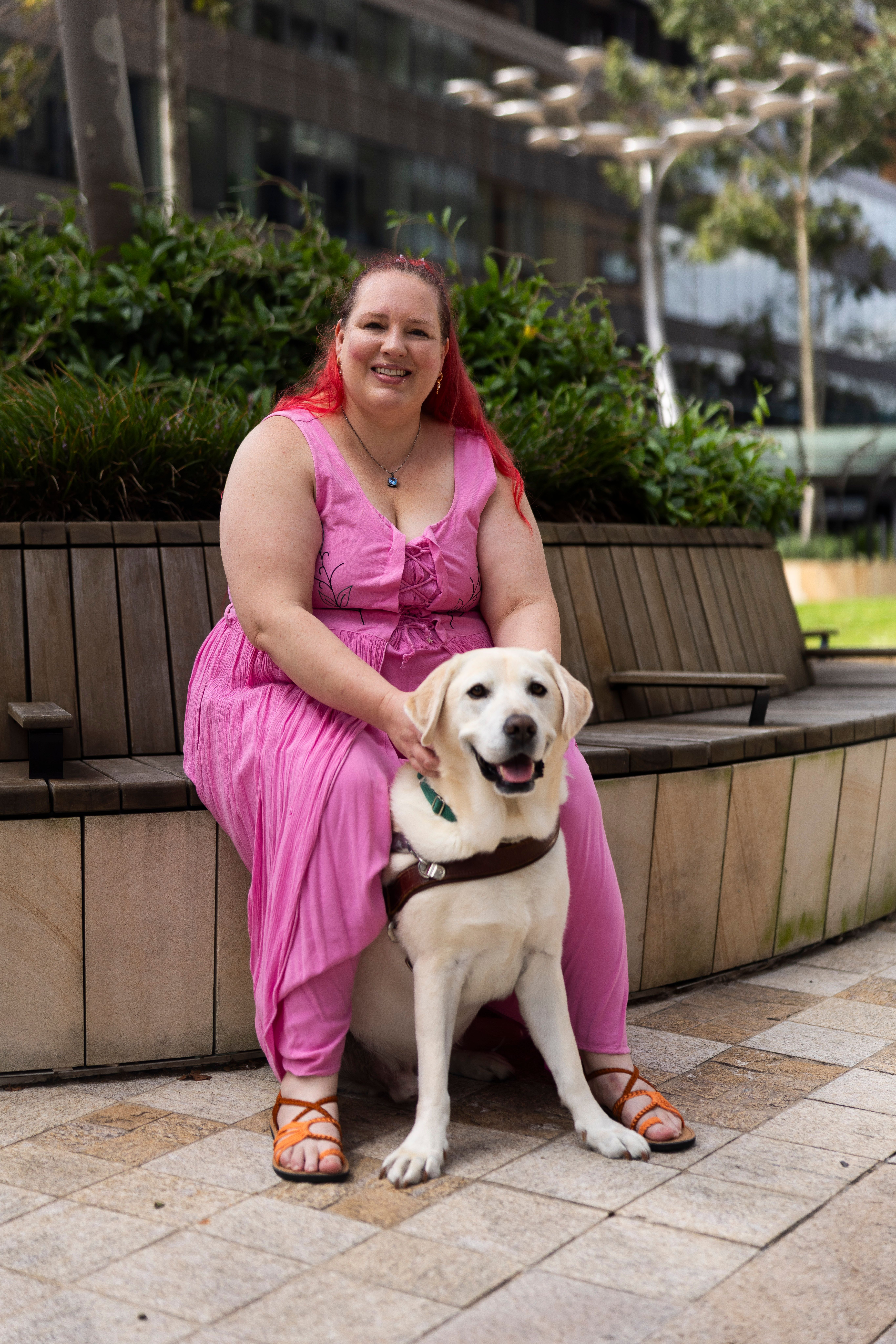 A person sitting with their Guide Dog. 
